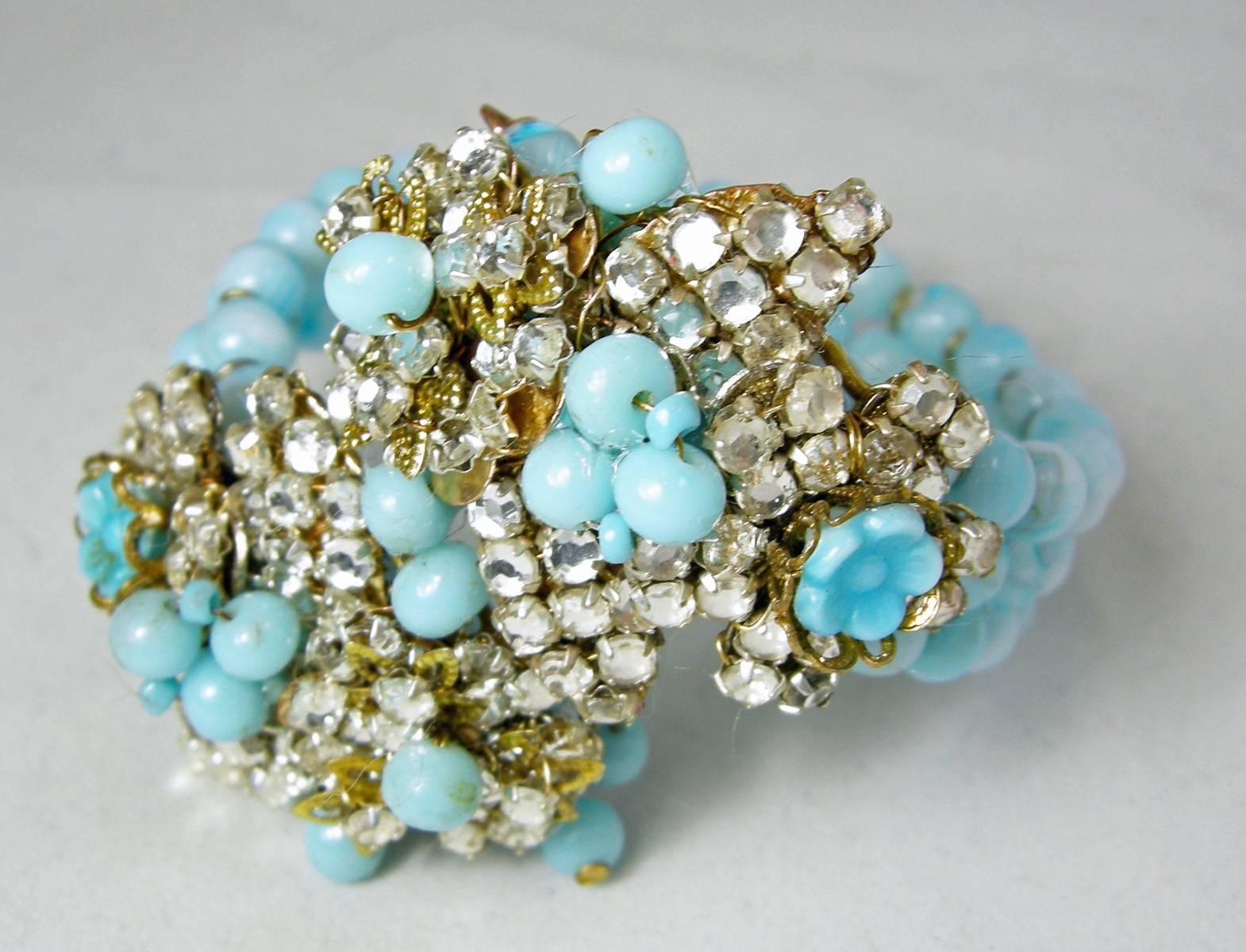 This rare vintage Miriam Haskell wrap around bracelet is from the late 1930s before she signed her jewelry.  It has 3 rows sky blue glass going leading to a floral centerpiece on both sides.  Blue glass flowers embedded in gold tone settings