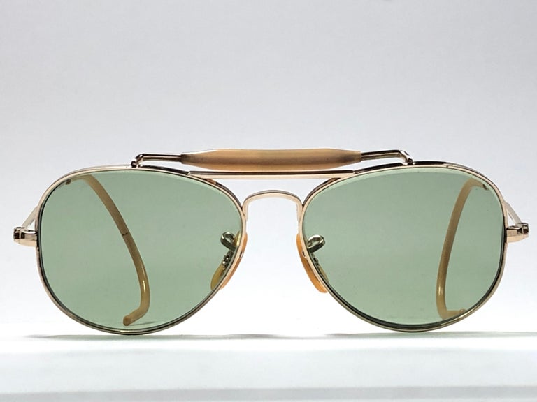 New Super special 1940's vintage Ray Ban Oudoorsmas Aviator 12K gold filled frame with light green lenses.
The smallest size available, suitable for children.  
This piece is a seldom piece. A real piece in sunglasses history.

Front : 10cms
Lens