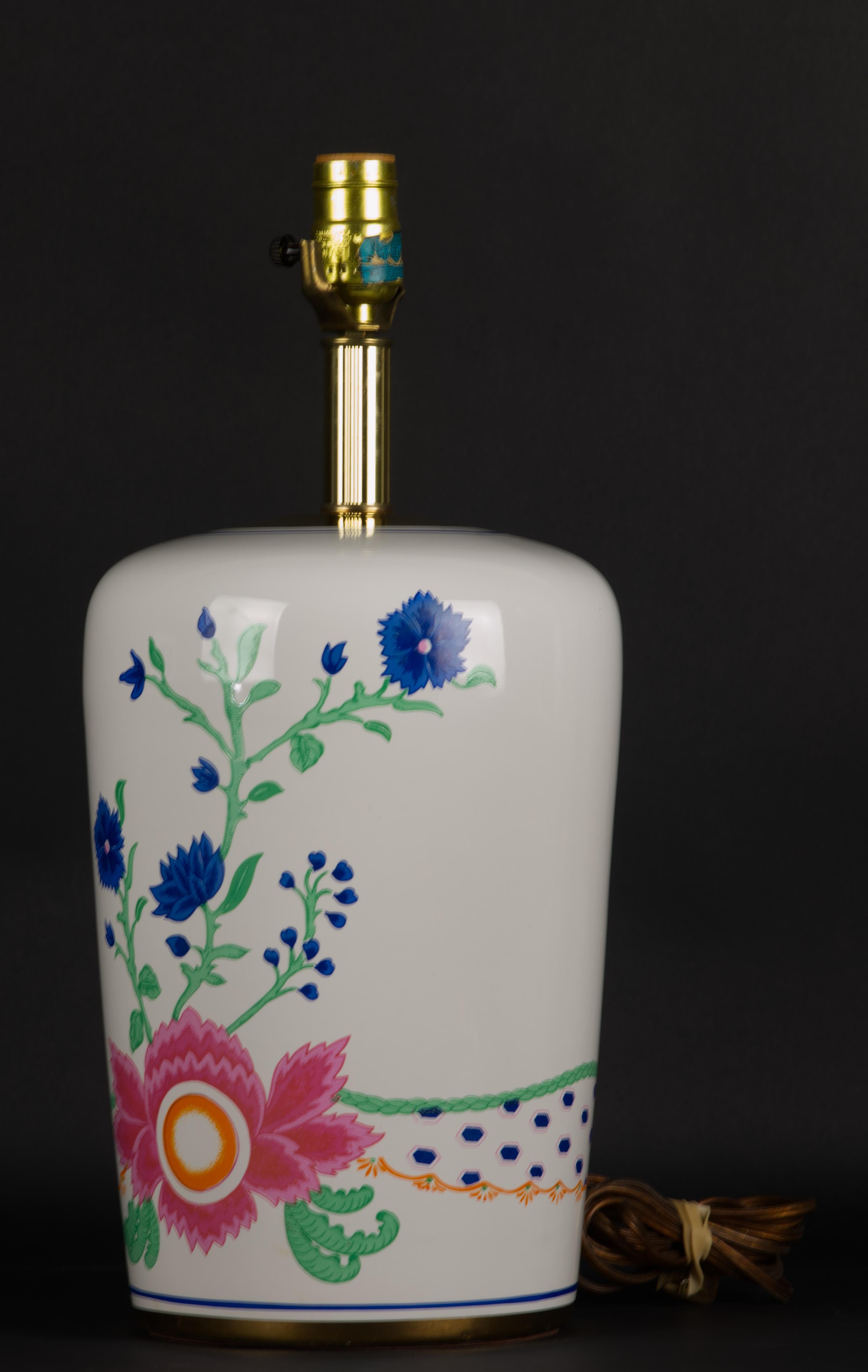 Vintage 1970s Westwood Industries Lamp company table lamp is decorated with abstract design of pink and blue flowers and green leaves on white porcelain body; bigger flower composition adorns the front of the lamp, and the back is done with smaller