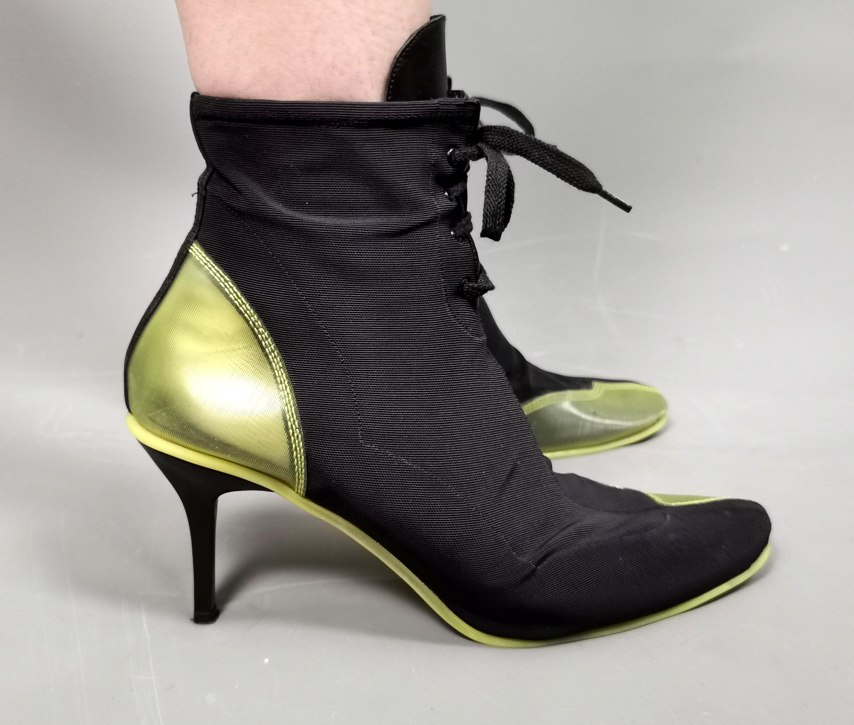 A rare pair of boxed vintage DKNY sneaker boots.

They are high heeled boots in a stretchy black canvas with a neon yellow rubber heel and half toe design which is slightly see through.

The boots have textured neon yellow soles.

They come in the