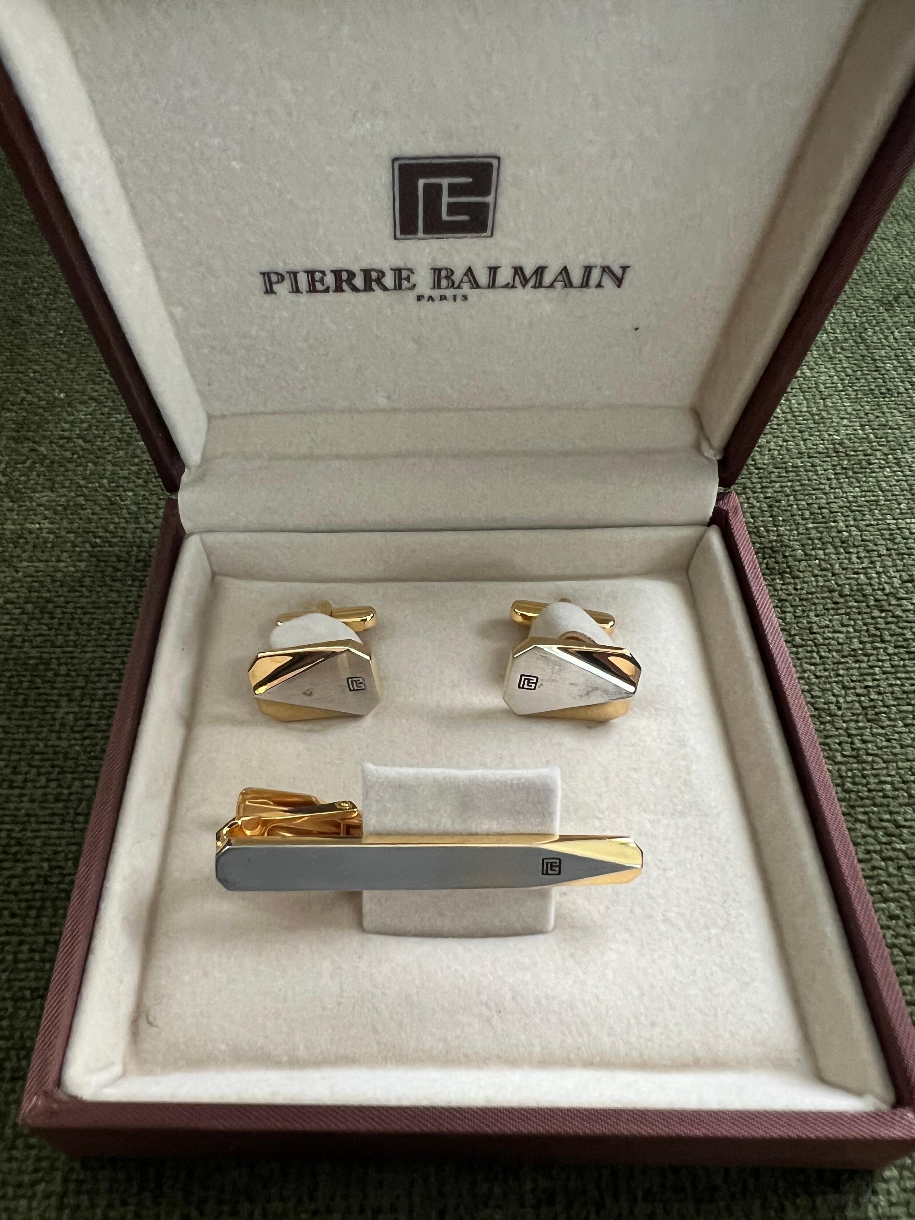 Rari gemelli e fermacravatte Balmain anni '80 in un astuccio originale di velluto e raso color champagne, CIRCA 1980
Placca d'oro e Steele 

Questi gemelli vintage Balmain degli anni '80 sono un must per tutti gli appassionati di moda. Realizzati in