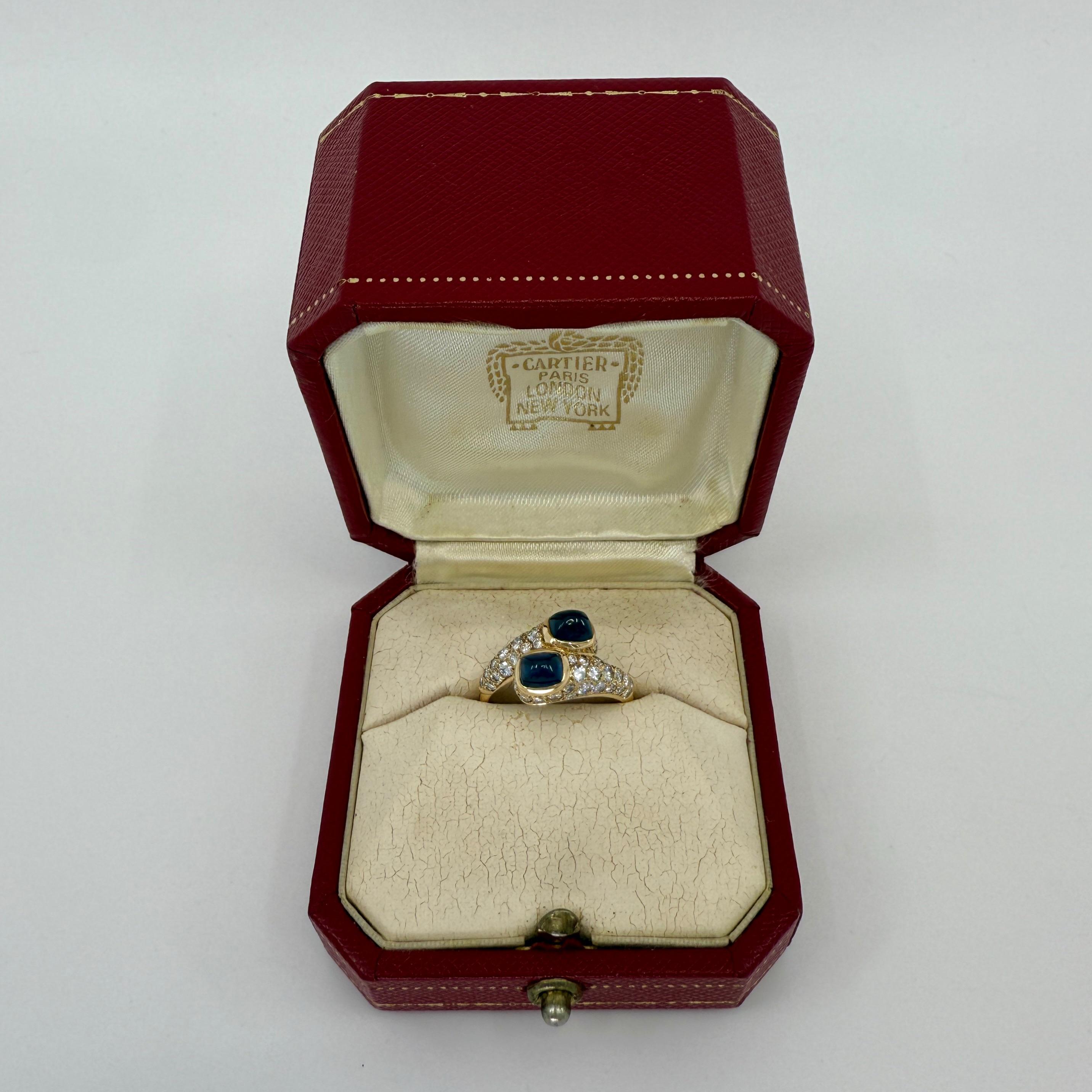 Anello Mimi d'epoca Cartier Sugarloaf con zaffiro blu e diamanti in oro giallo 18 carati.

Un rarissimo anello di Cartier con una coppia di splendidi zaffiri naturali taglio cabochon a forma di pan di zenzero, dal colore blu intenso e