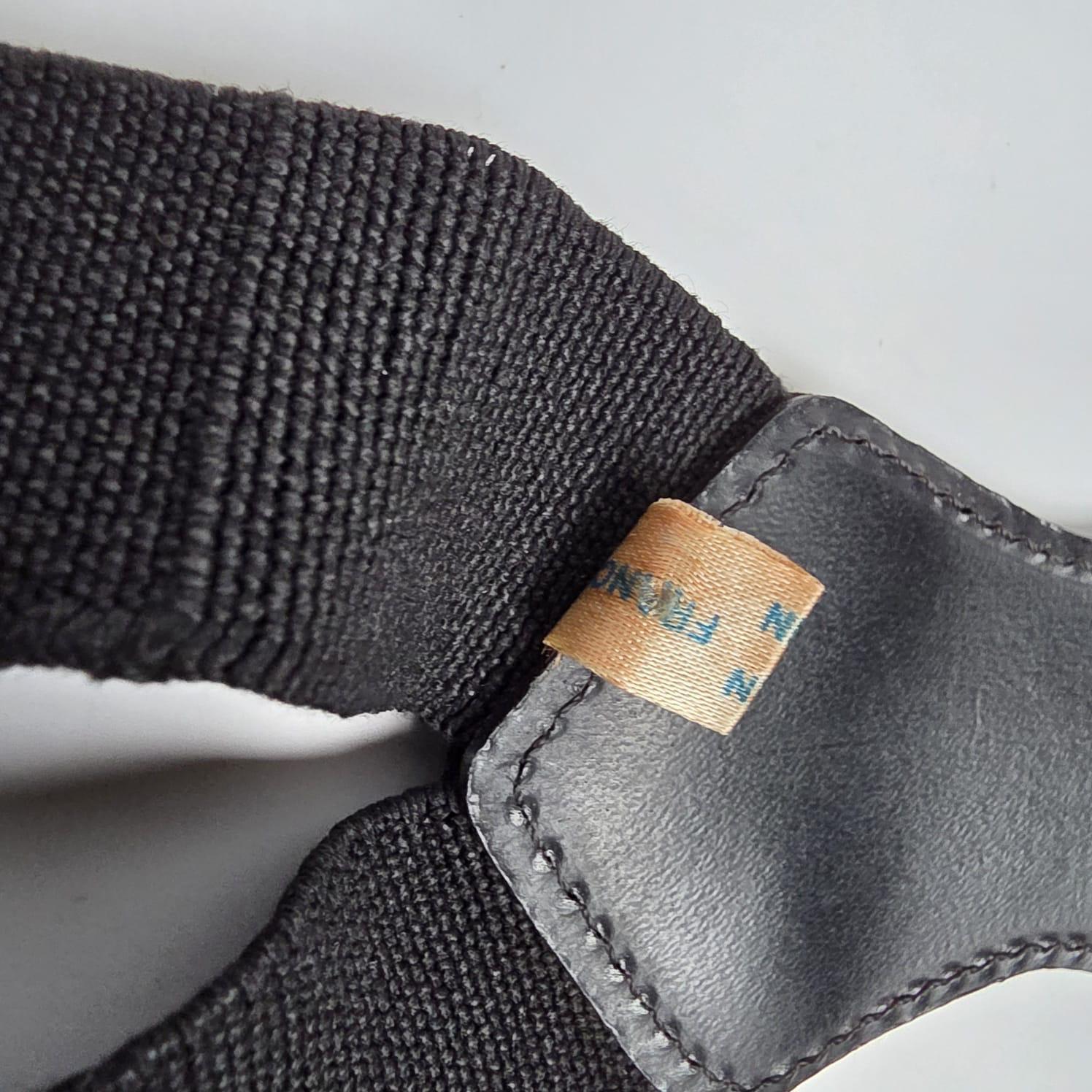 Klassischer Chanel-Sammelstraps in Schwarz mit weißem Logodruck. Leichte Gebrauchs- und Lagerungsspuren. Stretch-Stoff etwas locker, aber einstellbar. Geringfügiges Anlaufen der Beschläge. Wird mit Box geliefert.