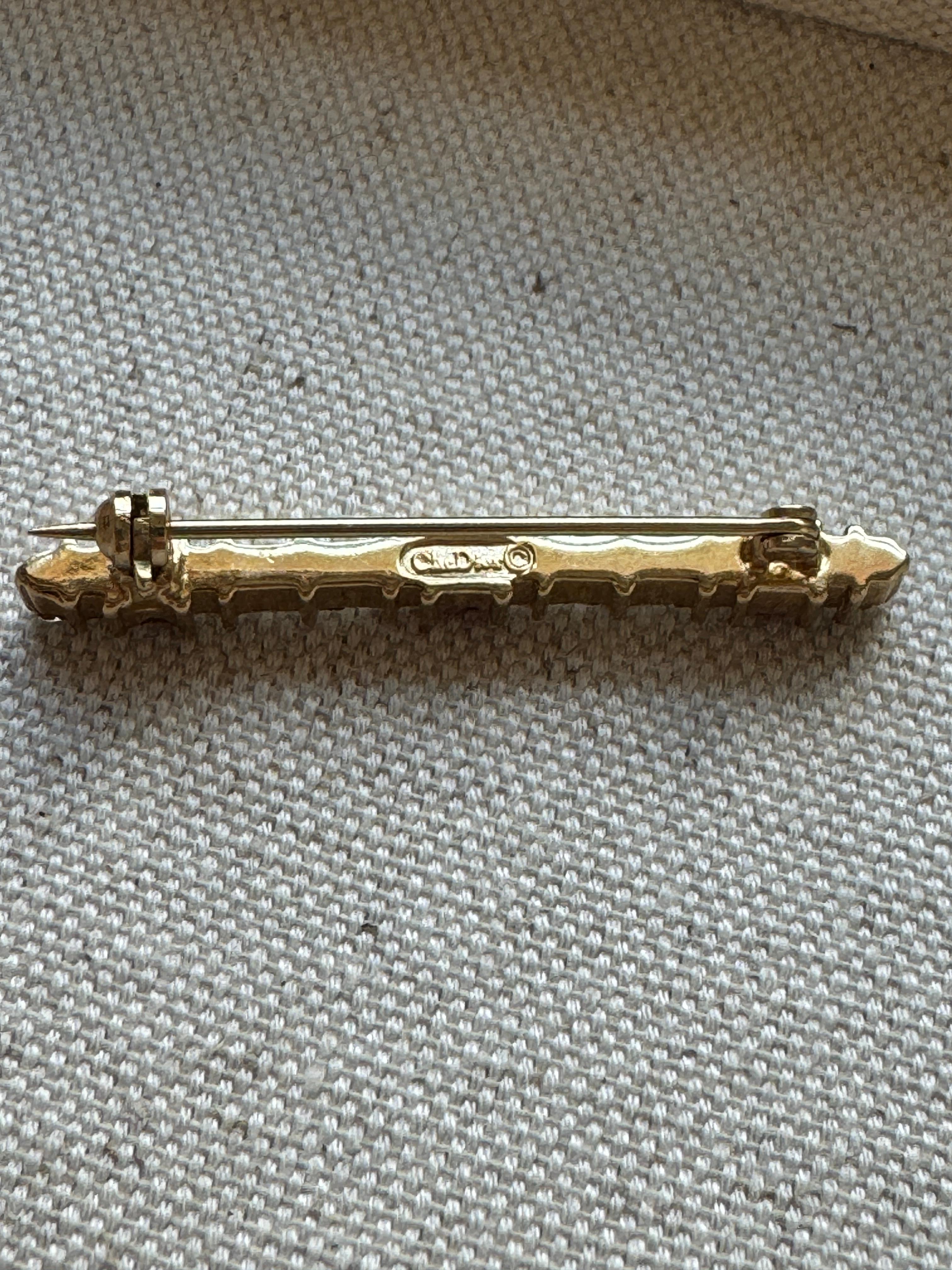 Broche vintage Christian Dior en tono dorado con piedras blancas y rojo granate intenso. 