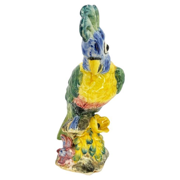 A rare colorful brightly glazed polychrome ceramic bird by Stangl. A gorgeous piece to add to (or begin!) a majolica collection. This porcelain piece features a green Parrot or Cockatoo with a yellow bust and beak and blue face. It sits upon a faux