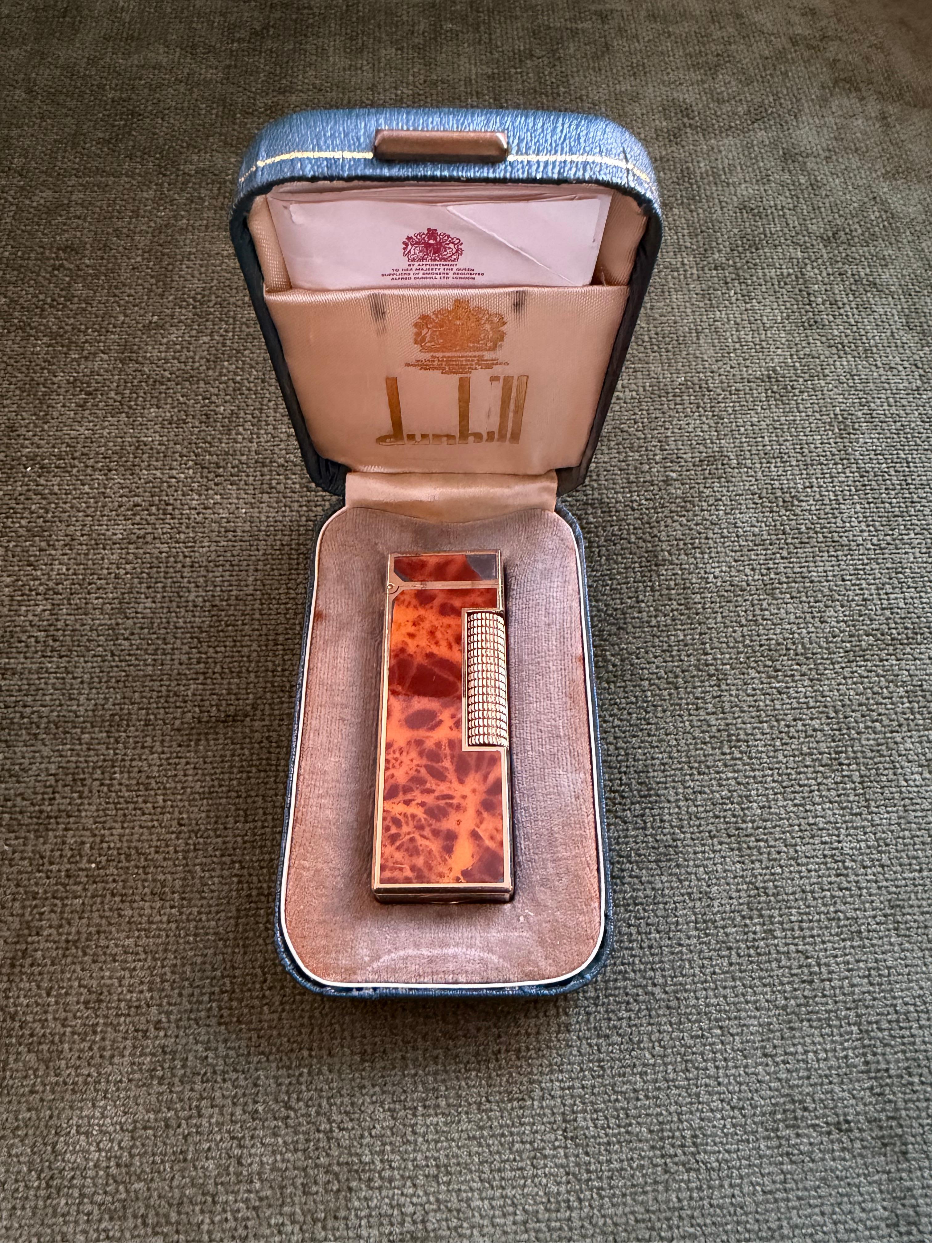 Raro accendino d'epoca Dunhill placcato in oro con lacca di marmo e cognac, con custodia originale in cielo, in condizioni super-miniate. 
Circa 1960
Edizione limitata 

Raro accendino vintage Dunhill placcato oro Cognac Marble lacquer Swiss Made In