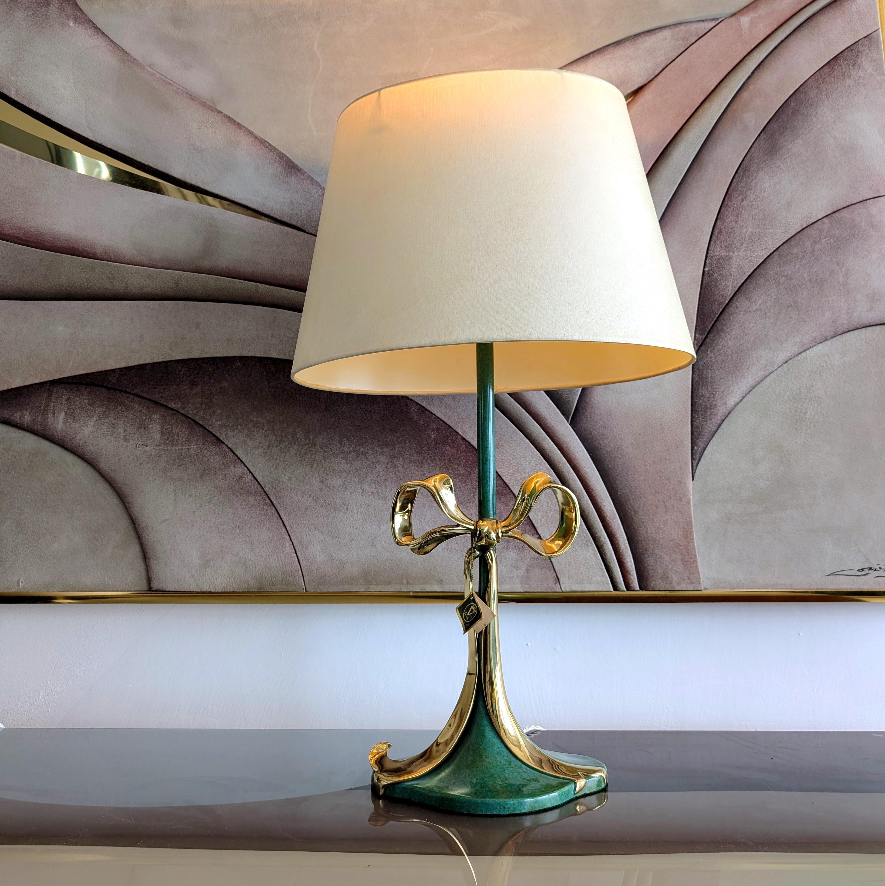 Rare bow lamp by Valenti, Spain, 1970s
Enameled bronze, with polished brass ribbon bow. Still has original Valenti tag.
Newly rewired with braided cord, complete with its original oval shade.

Dimensions: height to top of shade 74cm, height to bulb