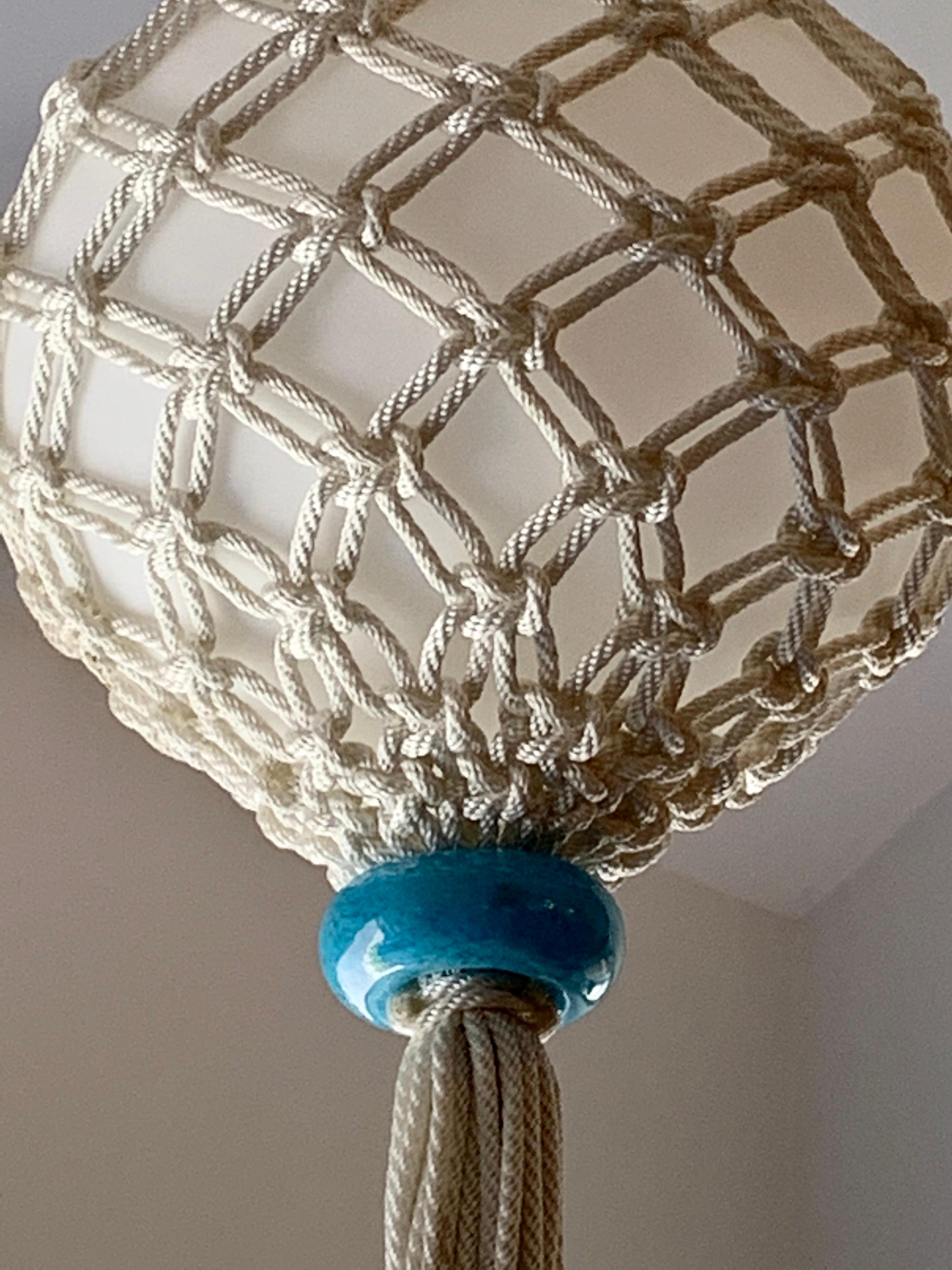 Very much looking like a marina floating buoy, this Murano glass globe is wrapped in beautiful polyurethane macrame rope. Two blue Murano glass adornments to top and bottom.