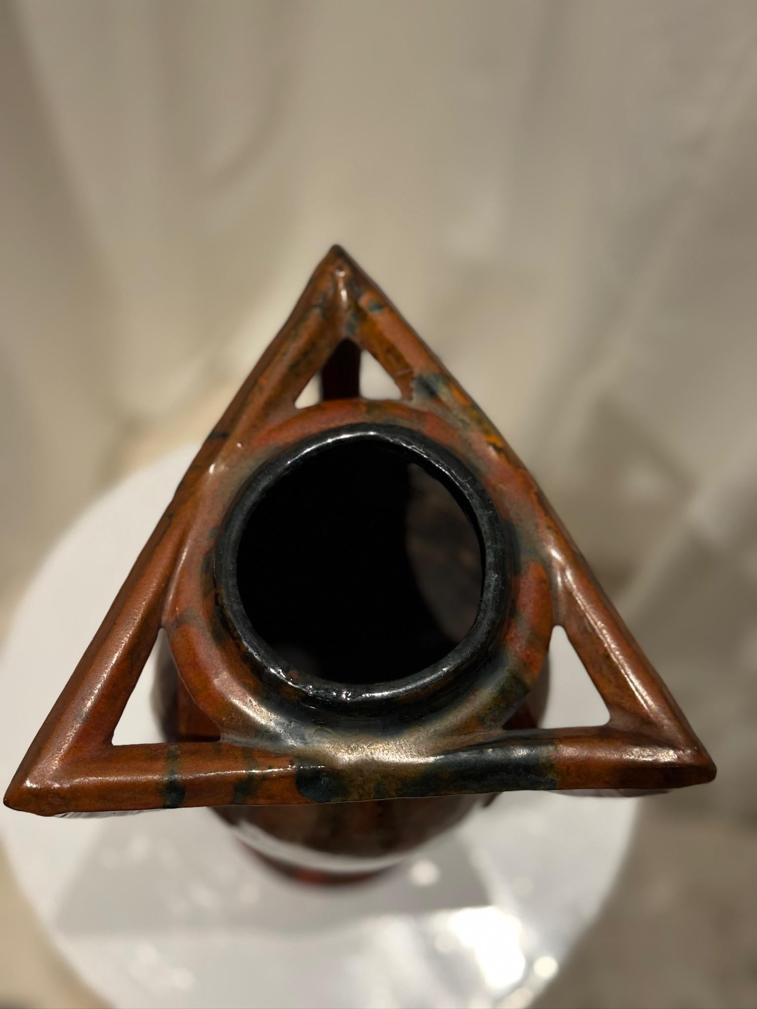 Questo squisito vaso vintage in ceramica Art Nouveau francese presenta un'armoniosa miscela di eleganza organica e design scultoreo. Il pezzo presenta una forma allungata e affusolata, accentuata dalle caratteristiche maniglie triangolari, che
