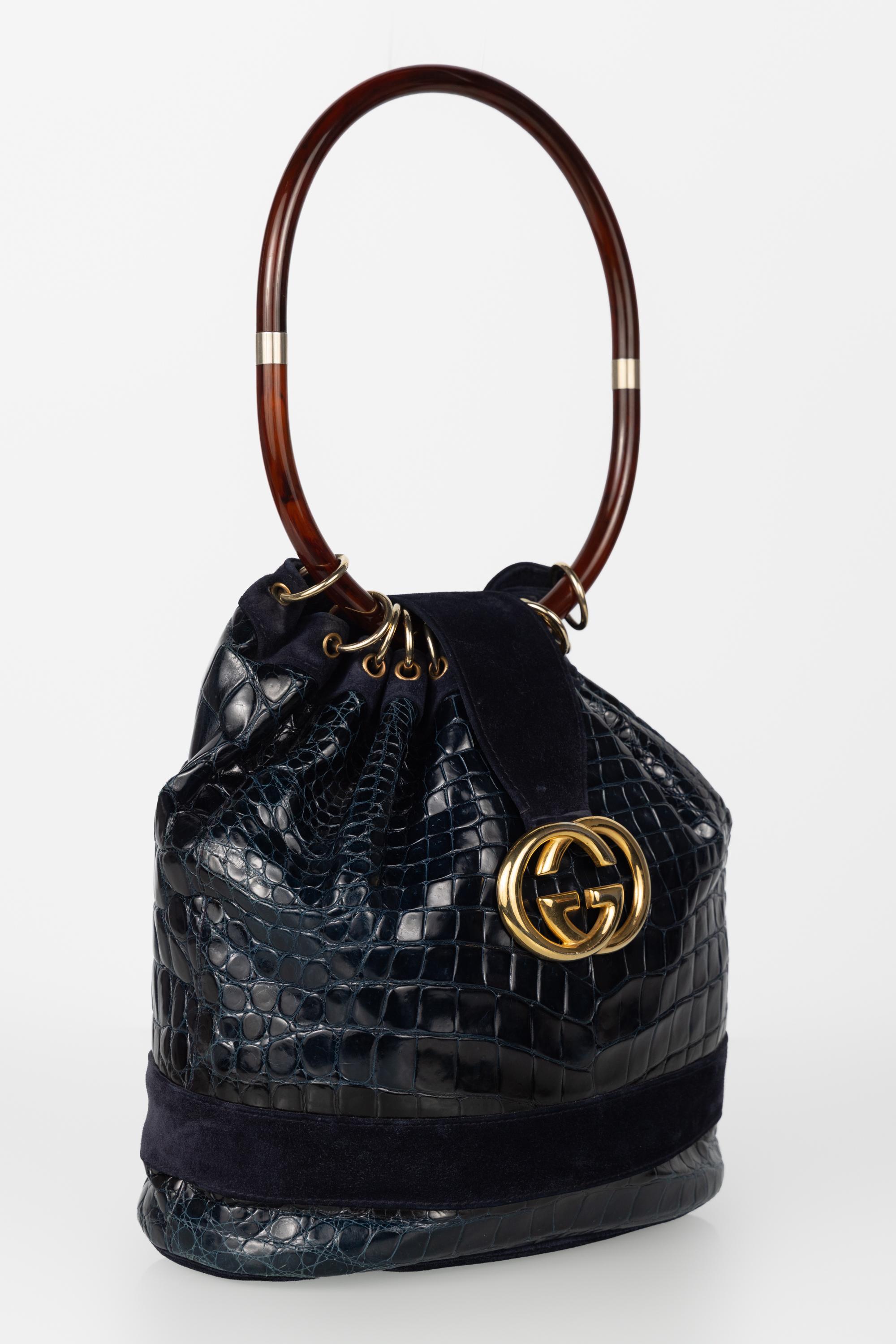 Una rara e scultorea borsa ad anello vintage di Gucci realizzata in pelle di coccodrillo color blu scuro con dettagli in pelle scamosciata. Questo pezzo risale alla fine degli anni '70 e all'inizio degli anni '80, un'epoca d'oro di sperimentazioni