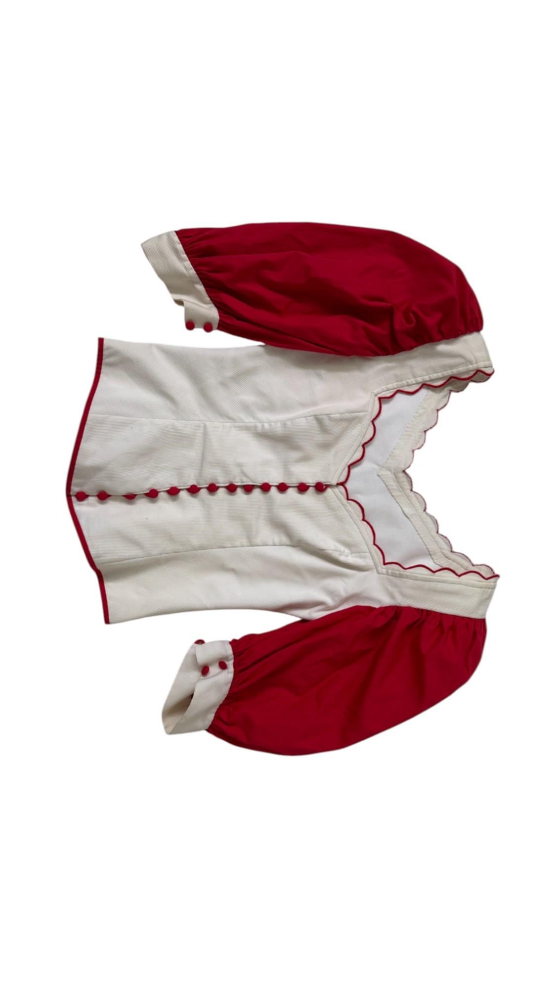 Diese außergewöhnliche und romantische Vintage-Bluse verbindet theatralische Eleganz mit volkstümlichem Charme. Das wahrscheinlich in den 1970er oder 1980er Jahren handgefertigte Kleidungsstück besteht aus einem schön strukturierten Mieder aus