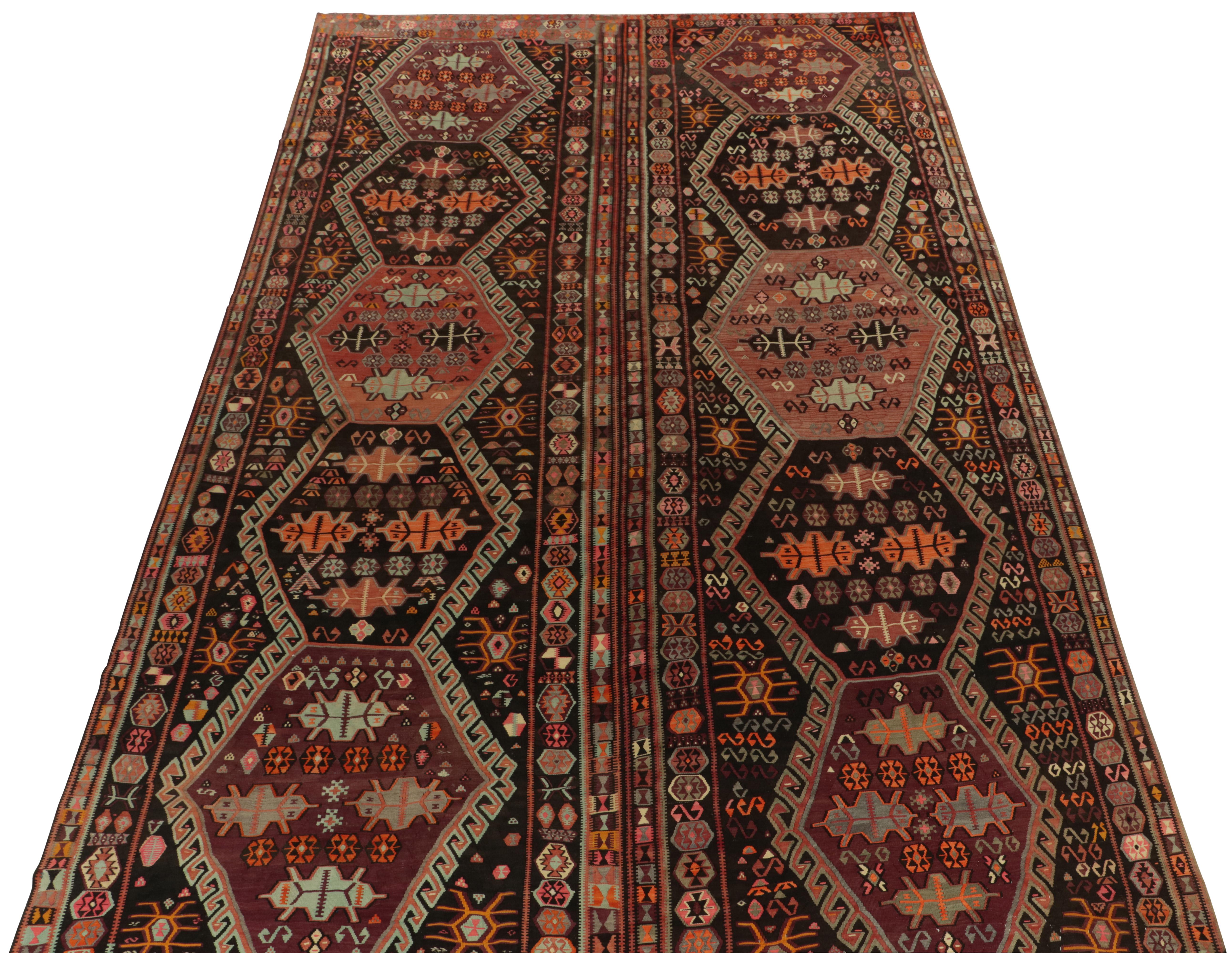 Originaire de Turquie vers 1950-1960, ce rare tapis kilim incroyablement tissé à la main fait partie de nos sélections vintage. Exclusif dans la pagination de ces teintes rafraîchissantes sur le fond le plus riche en marron, presque noir, avec de la