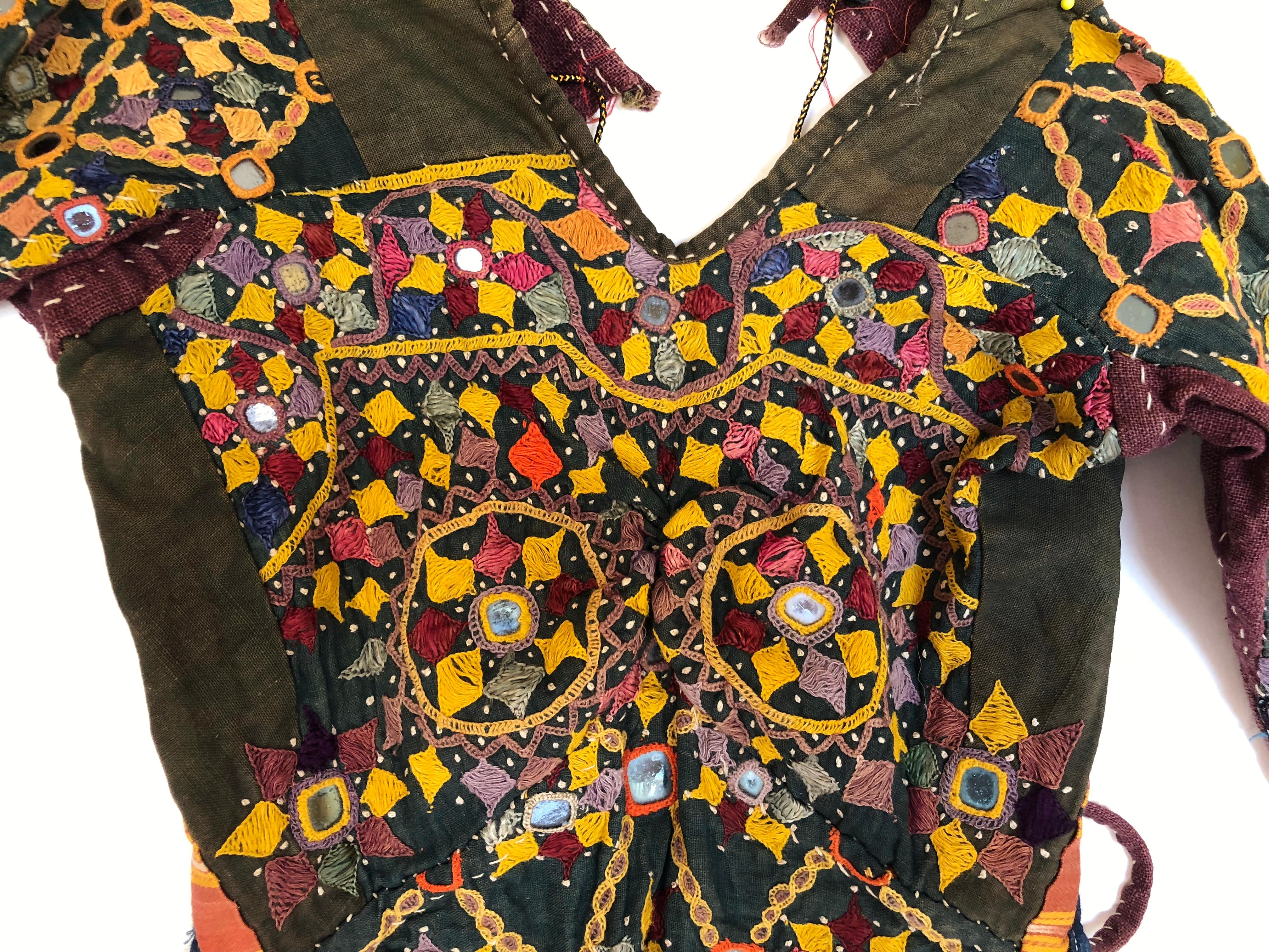 Rare vintage Kutch tribal Choli or blouse from India. The garment is made from handwoven cotton with heavy embroidery and mirrors. It is a woman's garment but very small in size with an open back and string ties. Photos show stitching on reverse of