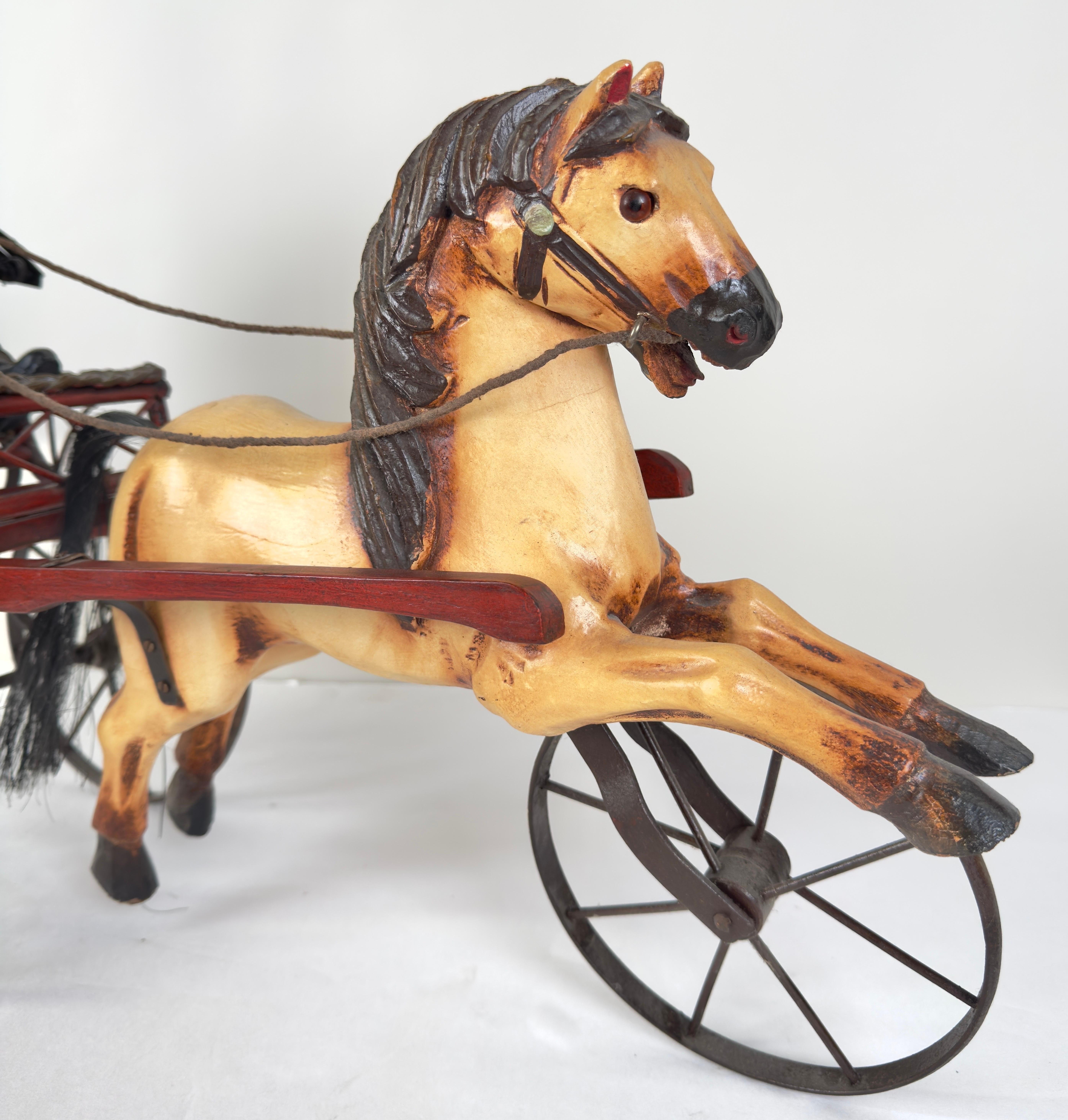 This rare early 20th-century hand-carved wooden sculpture portrays a horse and carriage with a man jockey. The sizable piece is finely carved, exhibiting astonishing details. The carriage, crafted from wicker, is fitted with metal wheels, and the