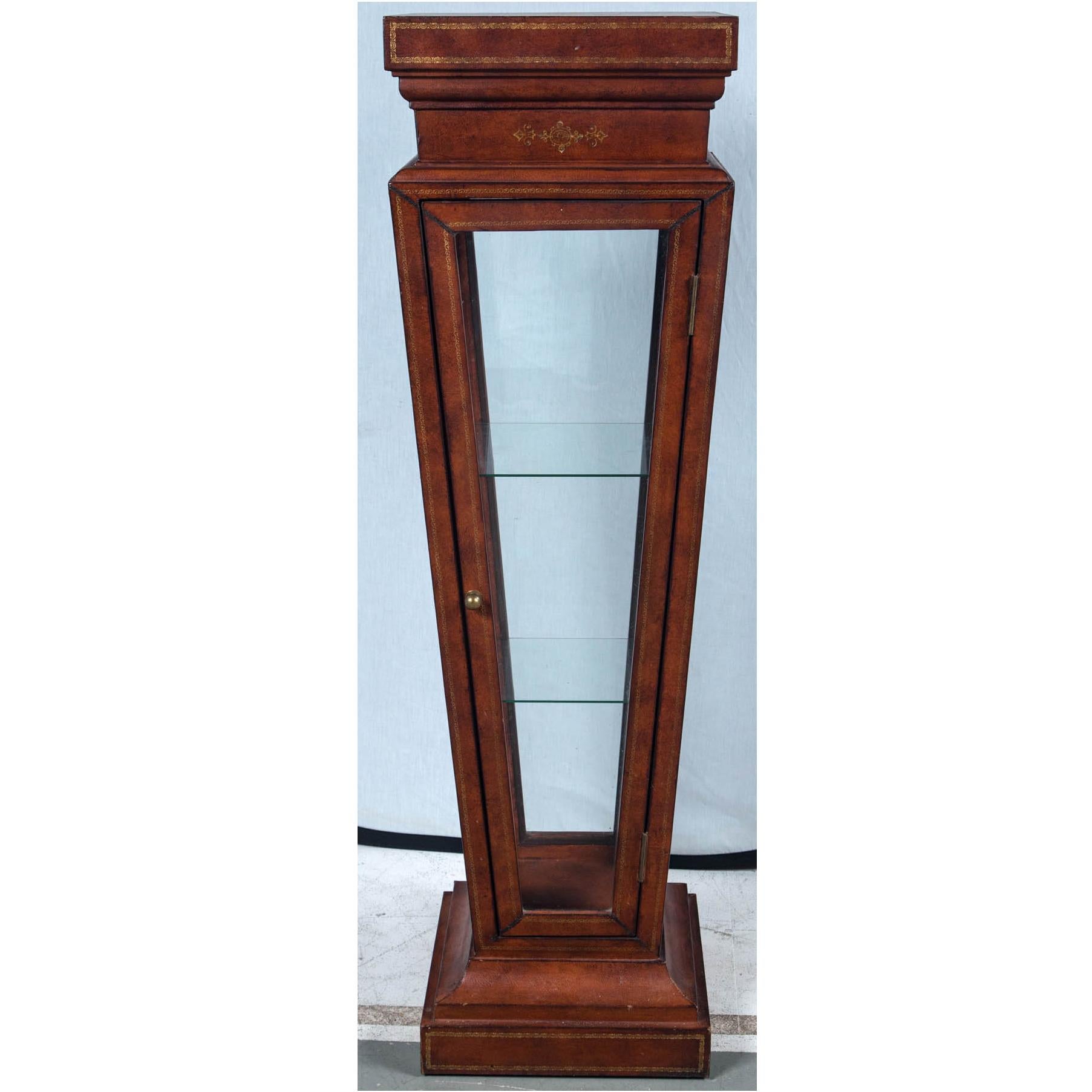 A fine and rare vintage 1950s leather-wrapped pedestal with gilt stylized decoration on the border. Having a vitrine glass showcase for displaying museum quality objects of virtue. Such a vintage decorative object was and is used in very high line