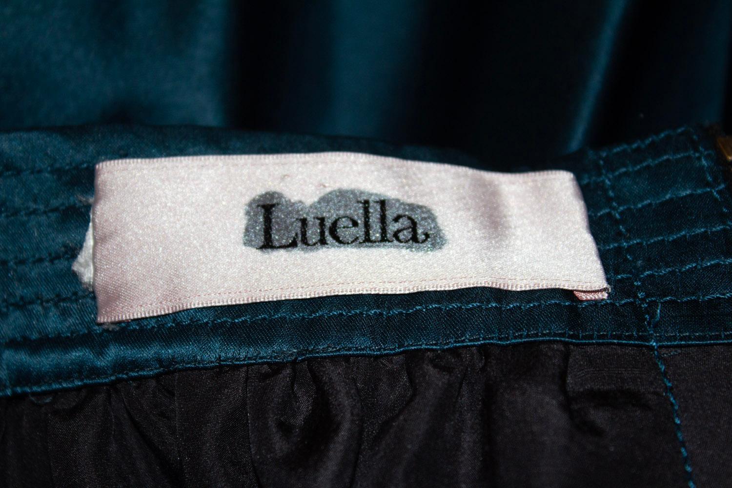 A stunning silk vintage evening skirt by Luella.
In a wonderful teal colour , the skirt has two  large pockets on the front with decorative buttons.  A back zip opening with decorative bow detail at the back., plus a full underskirt.
Size 36,