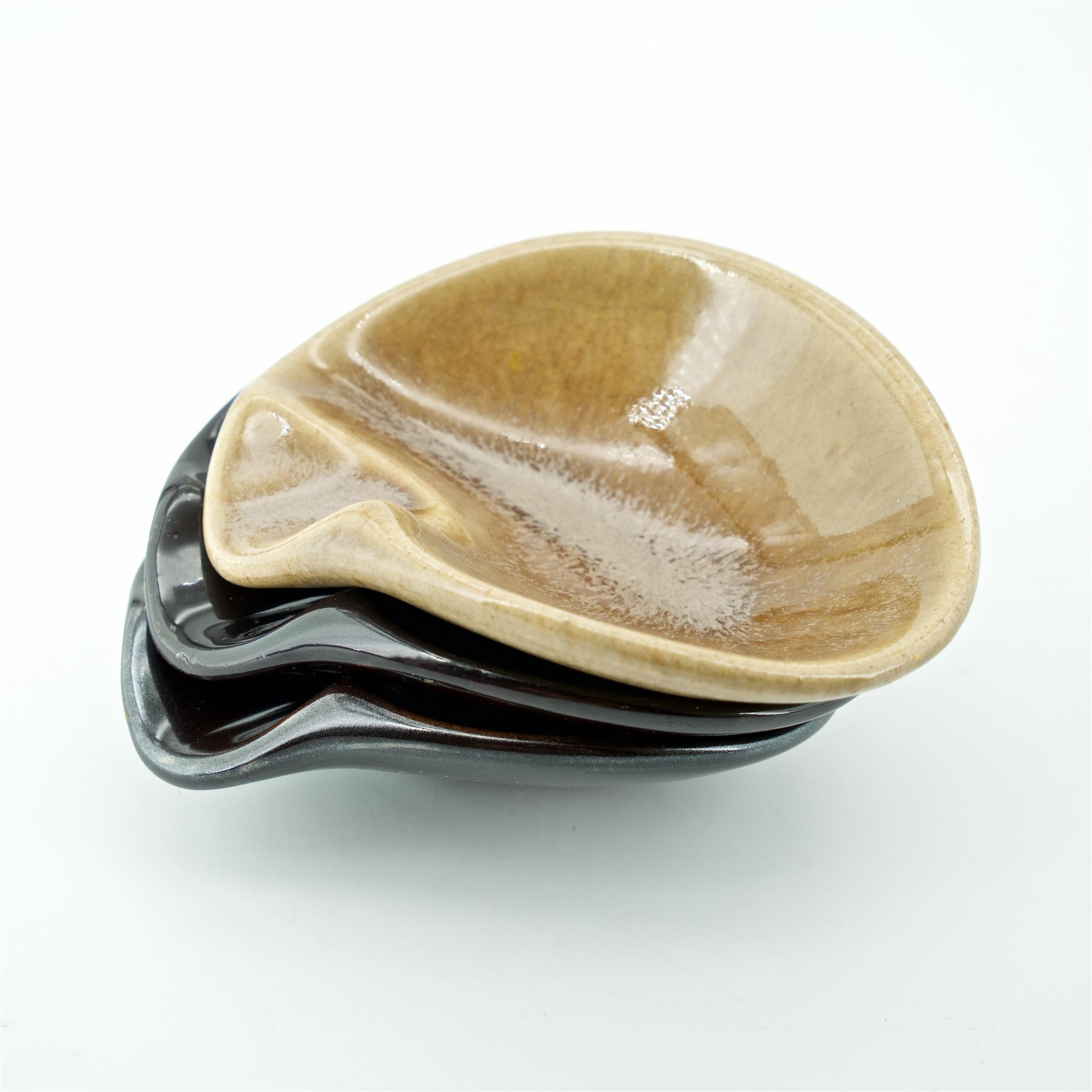Three organic ceramic bowls or ashtrays, that loosely stack. Black, Brown and Tan. All three signed, M.Negoro, and two with additional Alfred University info.  

Minnie Negoro (Japanese/American, 1919-1998) was born in California, but because of her
