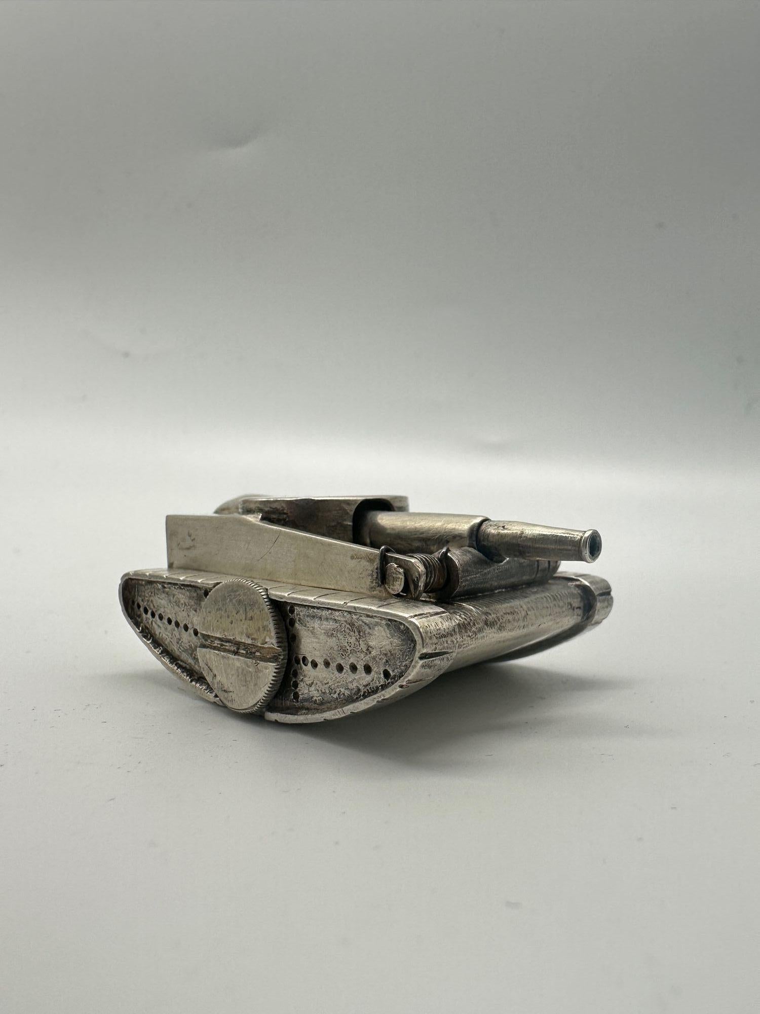 Das Design des Tischfeuerzeugs besticht durch eine längliche Panzerform, die an alte Artilleriegranaten erinnert. Die strukturierte silberne Oberfläche weist verschlungene Muster auf, die von der sorgfältigen Handwerkskunst und dem künstlerischen