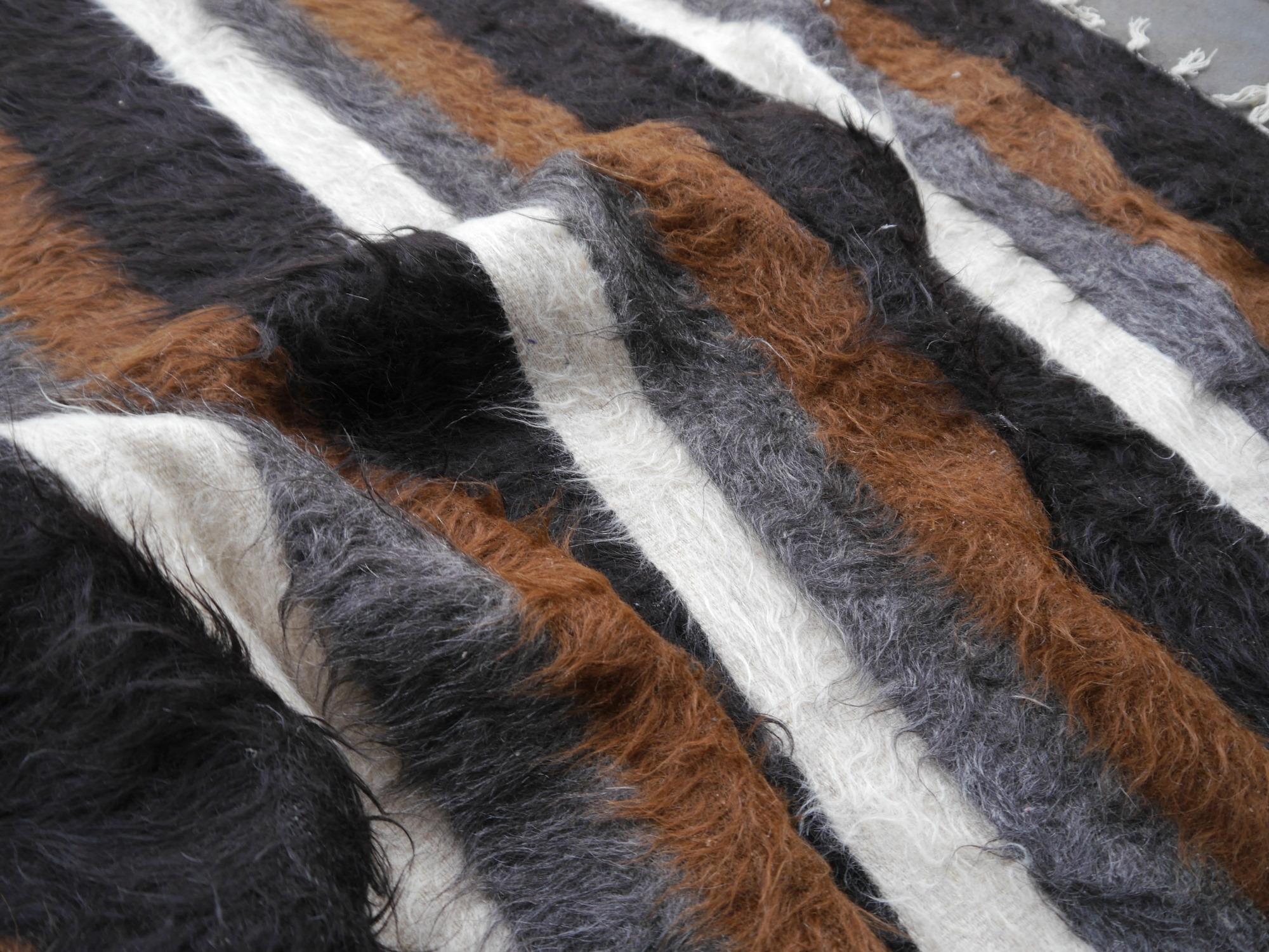 Dies ist ein Beispiel für die seltenen und schwer zu findenden Stammes-Mohair-Decken. Die Unterseite ist gerade gewebt wie ein Kelim, auf der Oberseite steht die Wolle aus der Decke heraus. Dies hält die Luft zwischen den Fasern und gibt eine