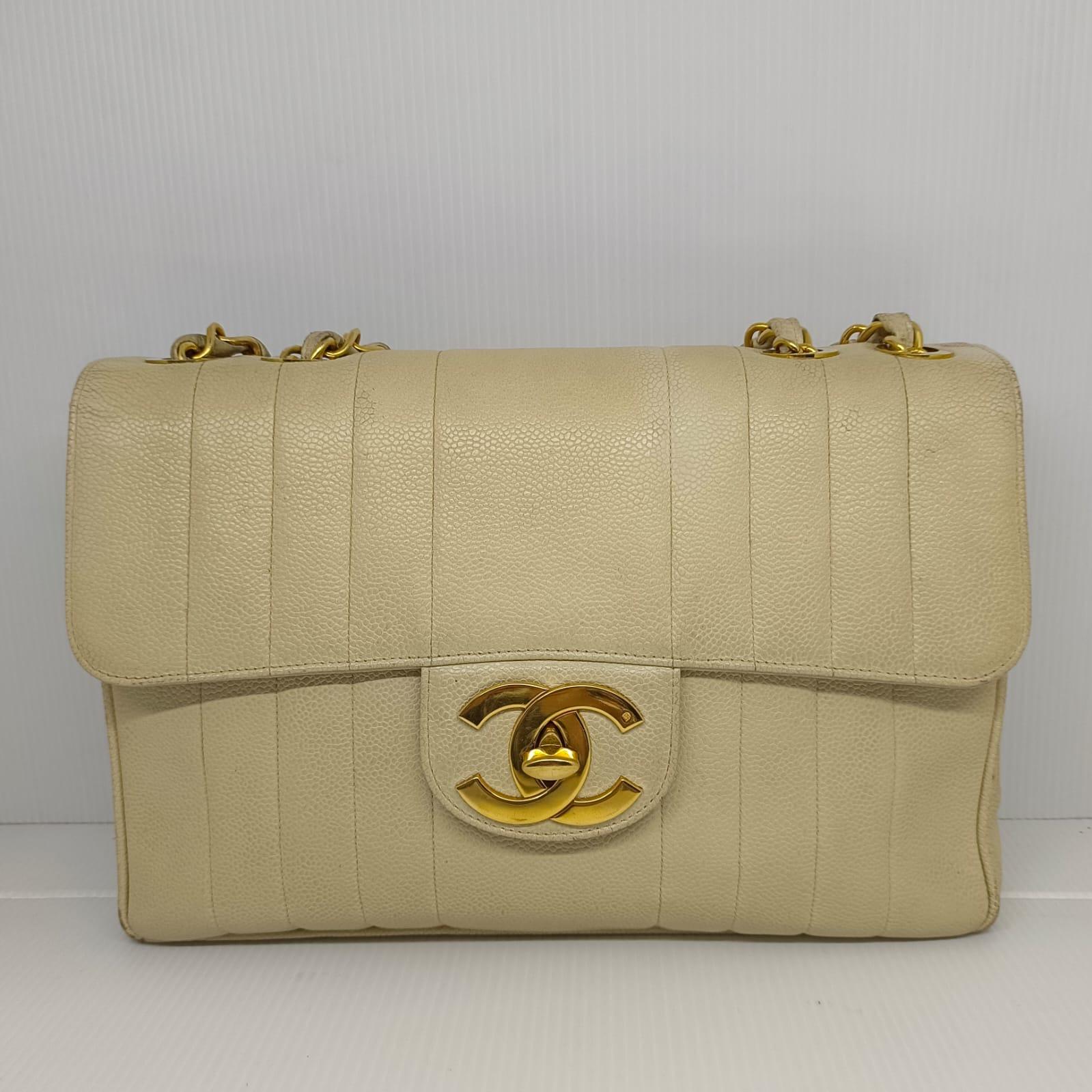 Seltene Chanel Vintage Jumbo vertikale gesteppte Tasche in off weiß Kaviar Leder mit 24k Gold Hardware. In getragenem Zustand, mit leichten Schmutzspuren auf der Lederoberfläche. Die Ecken weisen sichtbare Reibungsspuren auf und das Lederfutter ist