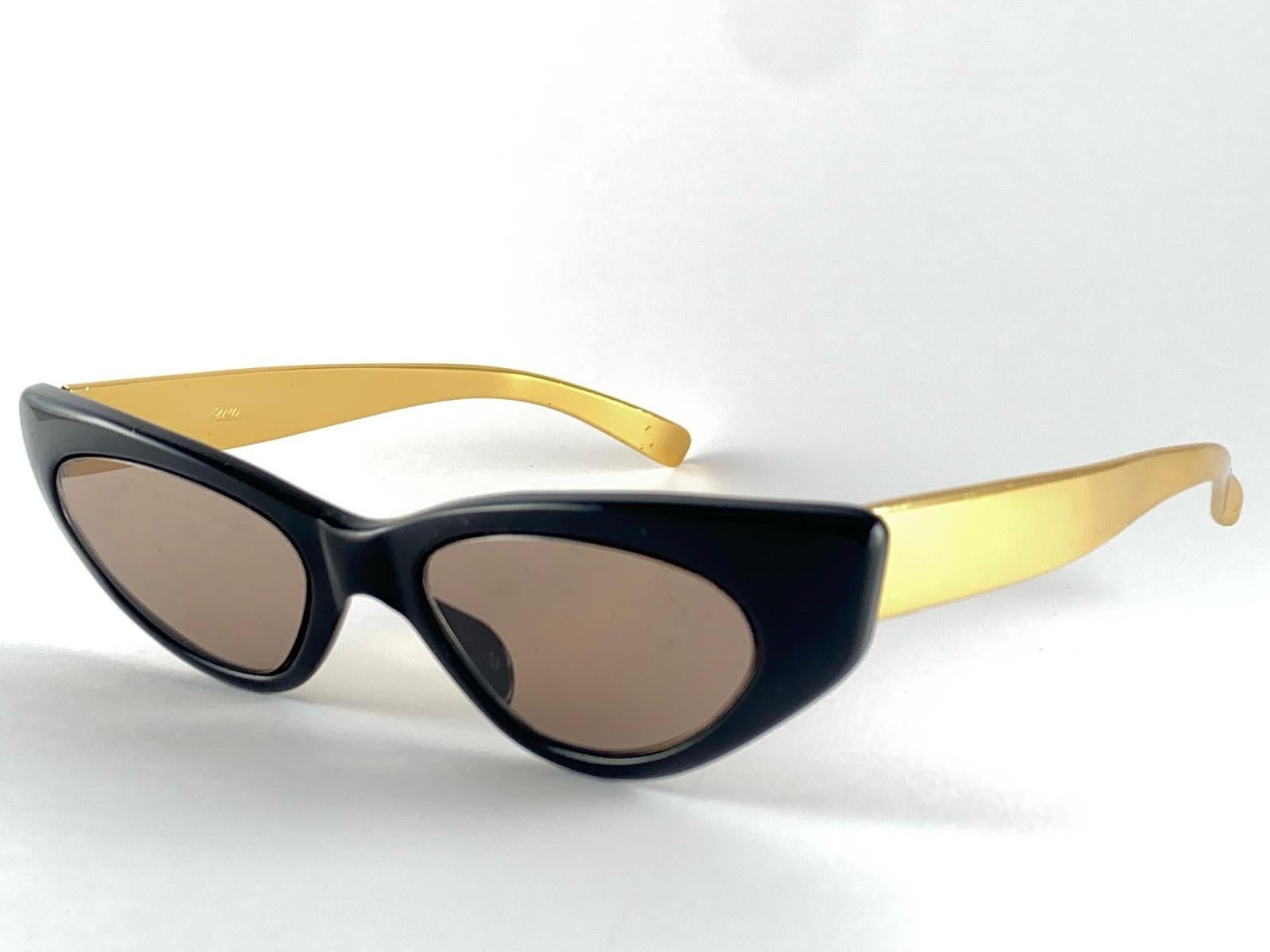 Seltenes Paar Oliver Goldsmith Sonnenbrillen. 

Schwarzer Katzenaugenrahmen mit goldenen Errebi-Seiten.

Ein seltenes und einzigartiges Stück in sehr gutem Vintage By Zustand. Spotless Hellbraun Linsen.

Vorderseite 13,5 cm
Höhe der Linse 2.8