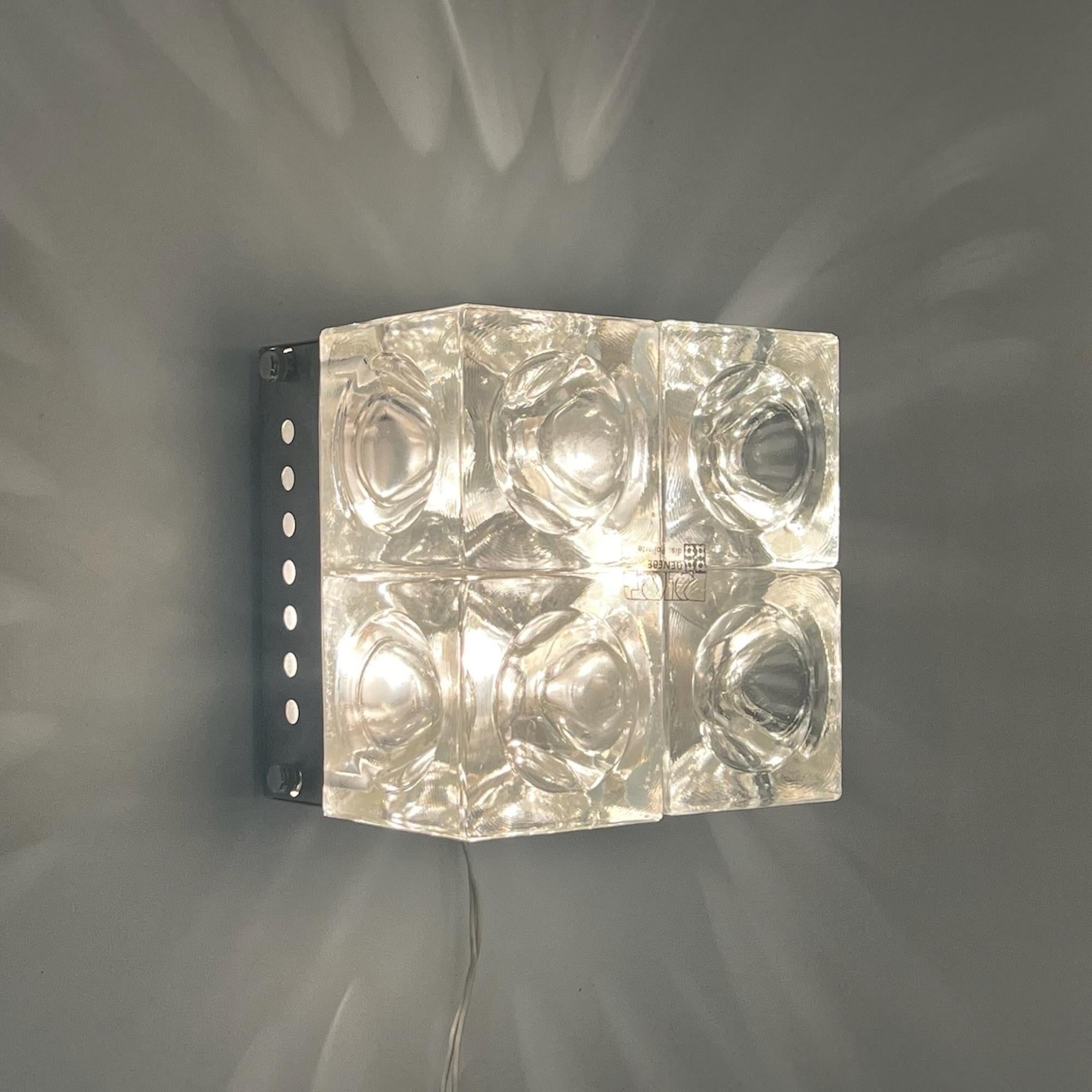 Découvrez la quintessence du design des années 1970 avec l'emblématique et rare lampe Poliarte, méticuleusement fabriquée par le maître Albano Poli. Ce chef-d'œuvre présente quatre cubes concaves en verre à bulles, sertis dans une base en métal avec