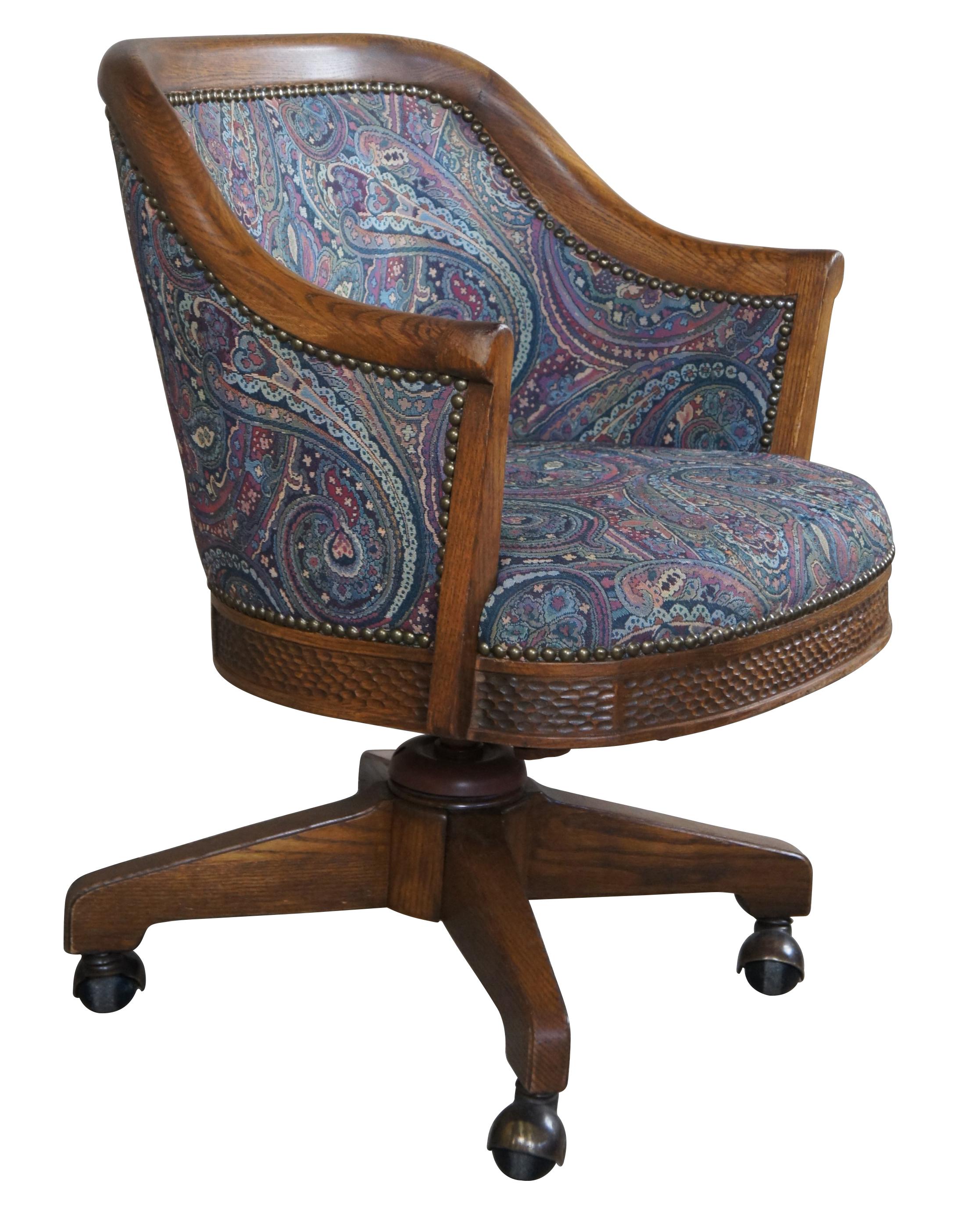 Romweber (R-18290) Viking Oak Swivel Desk Chair, circa 1980s. Features a barrel back design with flared arms, pasiley upholstery, brass nailhead trim, and a swivel base. The lower apron is neatly carved in a Nordic manner. An iconic piece from the