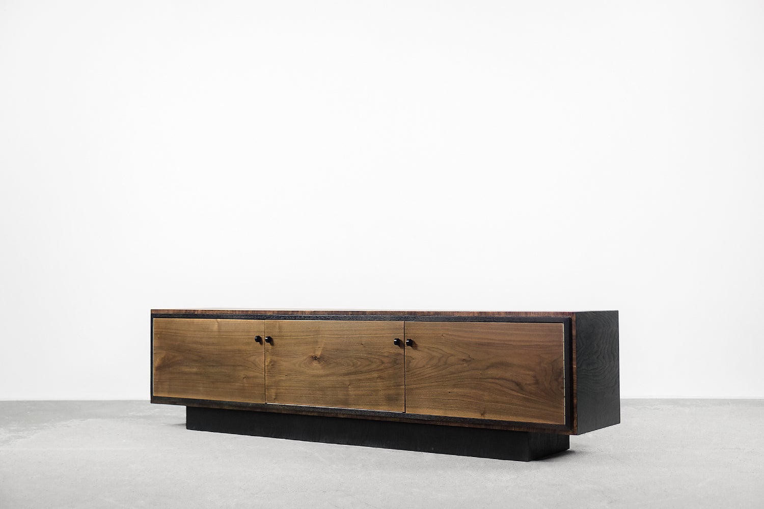 This rare sideboard comes from Scandinavia, where it was probably made during the 1960s. The top and sides are finished with walnut wood in elegant black, with a visible grain pattern. The front is in a natural shade of walnut with round handles.