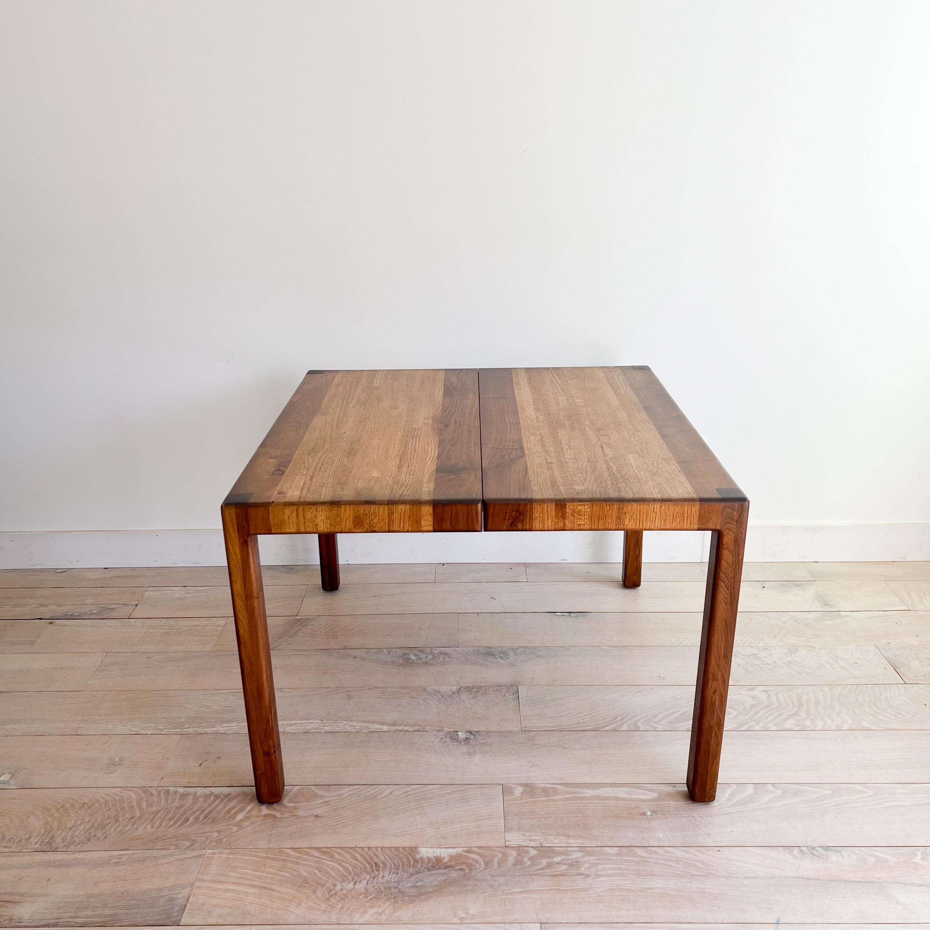 Add a touch of timeless elegance to your dining space with this exceptionally rare mid-century modern dining table designed by Lou Hodges in California. Crafted with precision from solid wood, including oak and walnut accents, this piece exudes