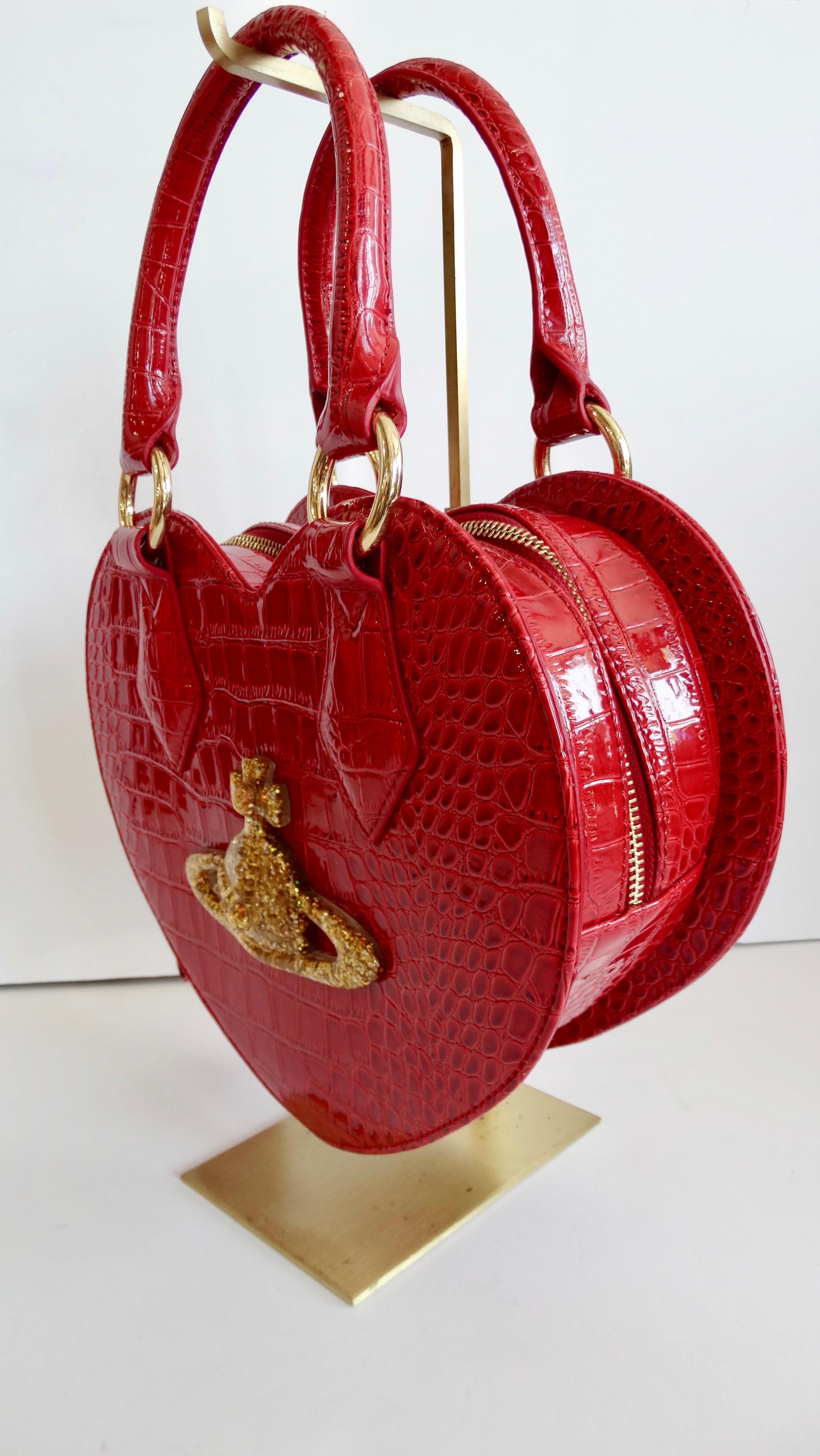 Show your love for Vivienne Westwood with this adorable vintage Chancery heart bag! Circa late 21st century, this rare heart bag is made of alligator embossed patent leather and features gold-tone hardware, dual top handles, and a detachable flat