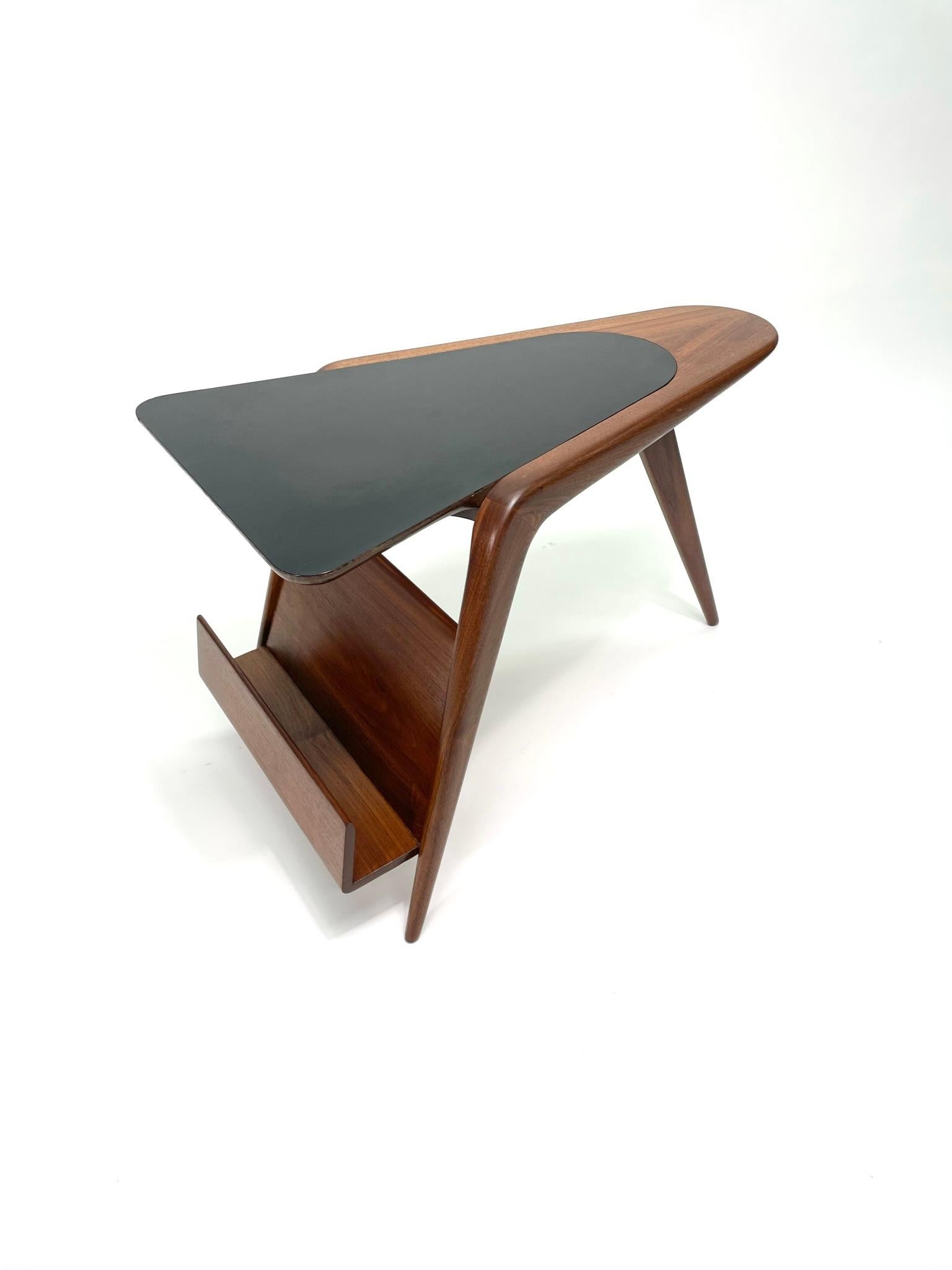 A very rare Kagan Occasional Walnut Side Table, circa 1950s. With a triangular wedge black laminate top and a walnut base with lower magazine shelf, this side table brings functional art to life. Featured a unique tripod base with Kagan's iconic