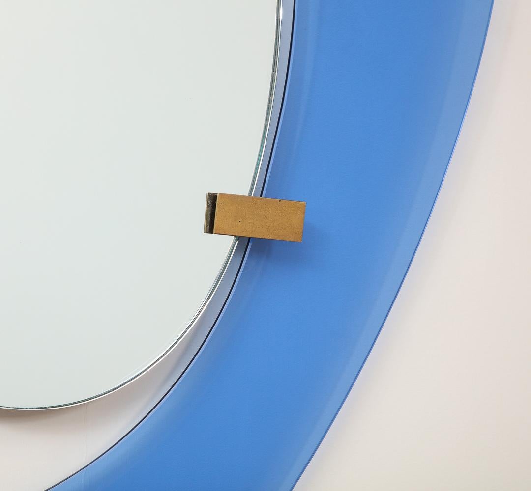 Farbiges Glas, Holz, Spiegel, Messing. Leuchtend blaue Glaseinfassung, mit schwebendem Zentralspiegel und Messingbeschlägen.