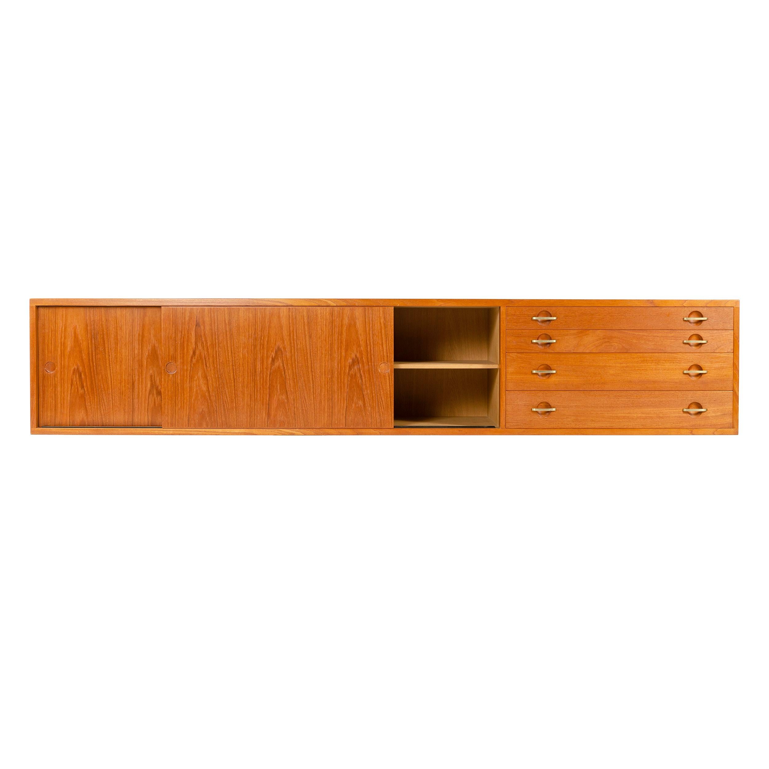 A teak wall mount credenza / cabinet with two sliding doors and four drawers. Designed by Hans Wegner, made by Johannes Hansen, Denmark, 1952.