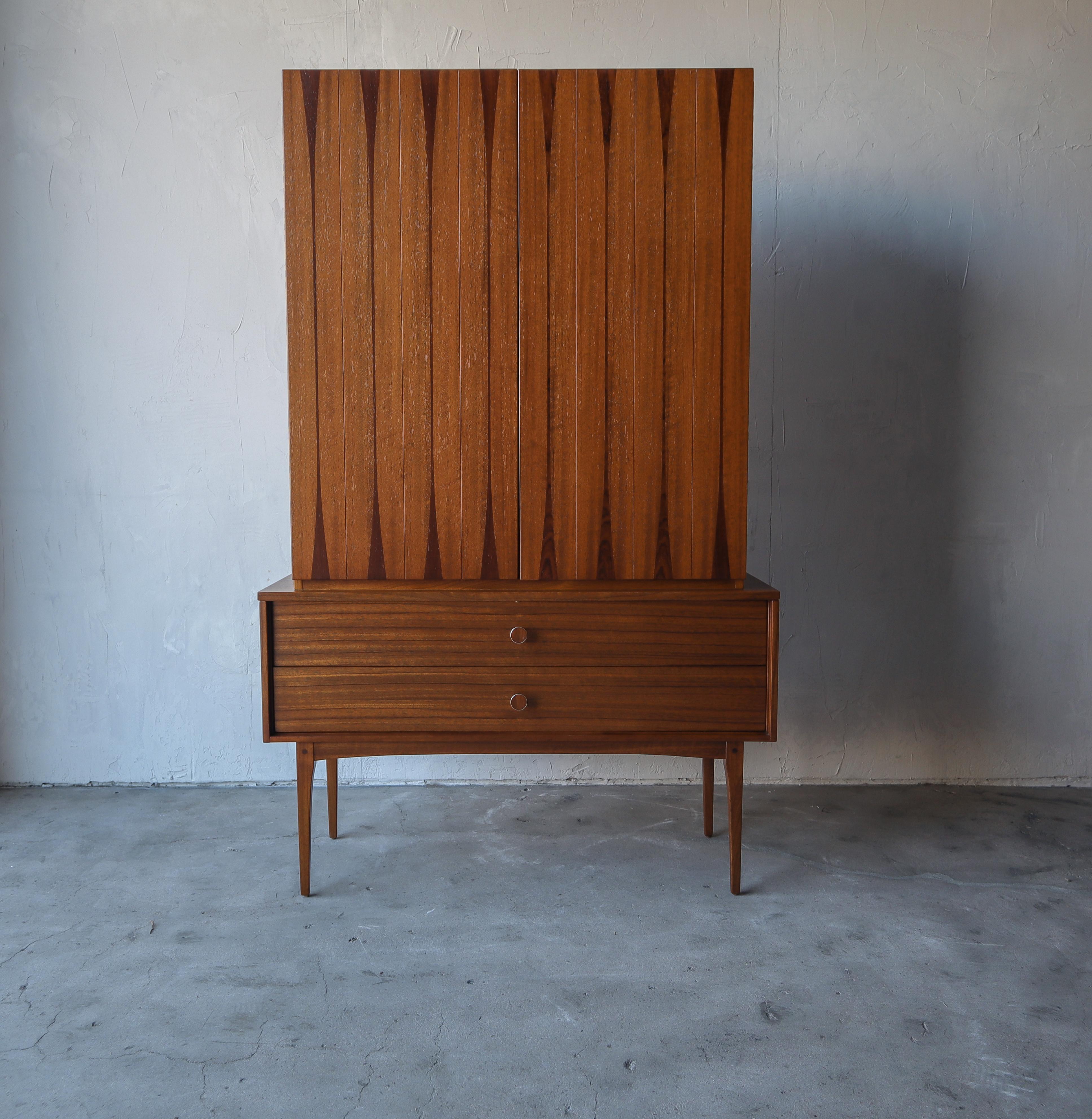 Super rare and early midcentury, armoire by Lane. This piece is absolutely beautiful. It's a stunning combination of walnut and rosewood with brass pulls that too are inlaid with rosewood. A gorgeous and feminine piece supported by 4 tall tapered