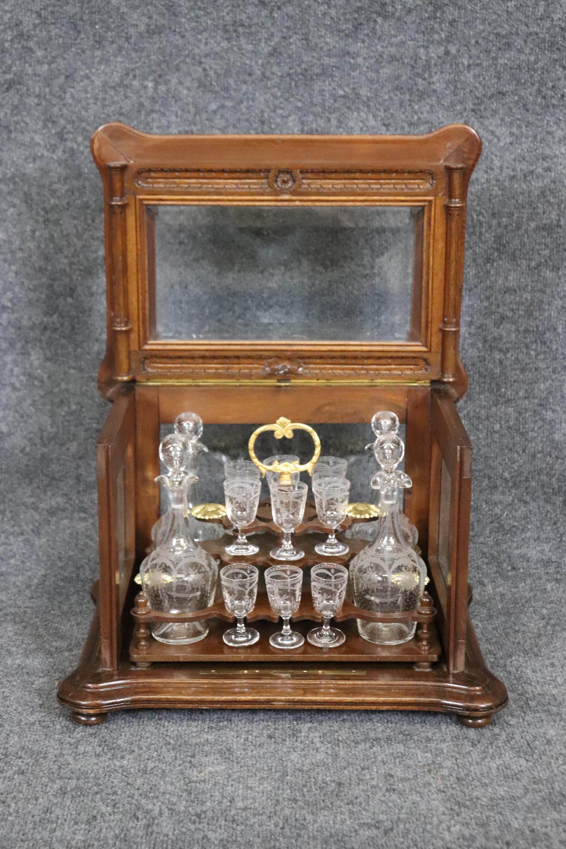 This is a superb tantalus with its original etched glass cordial glasses and etched glass decanters for whiskey or bourbon. The set is in very good original condition with entirely original finish in good condition and bright brass details inside.