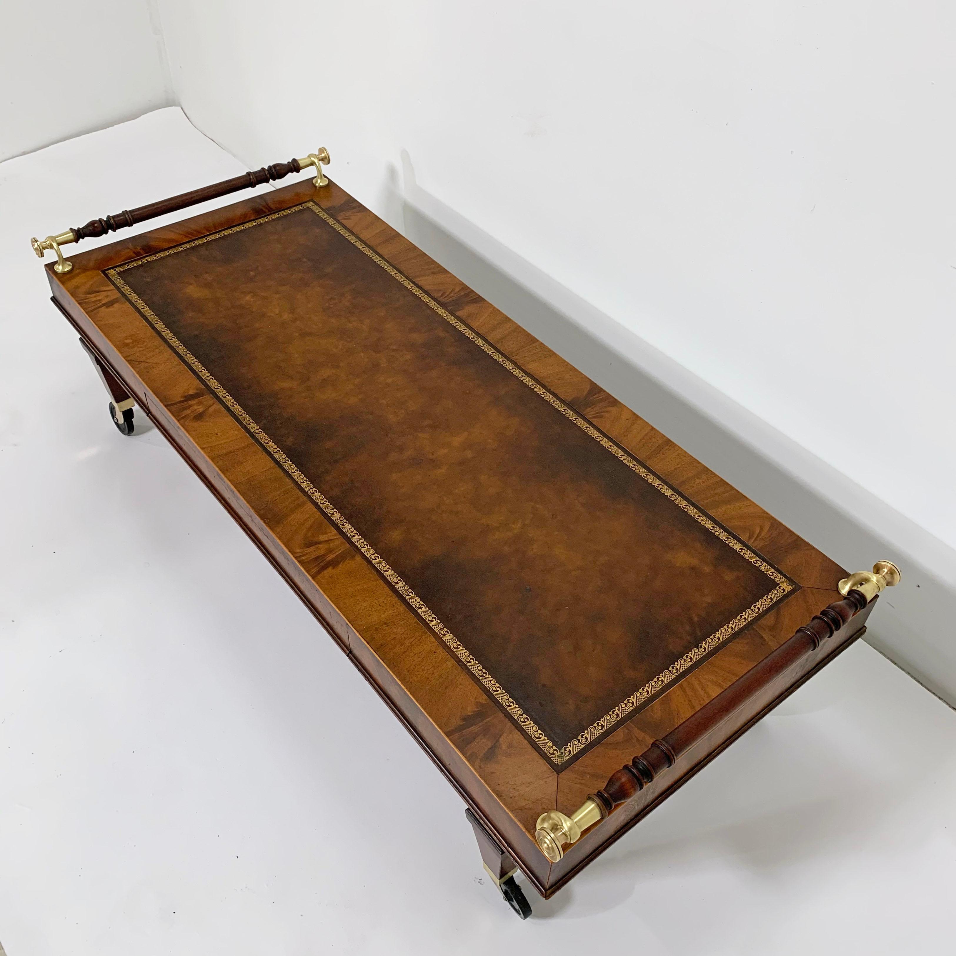 A rare form Regency style coffee table in mahogany with embossed leather top, turned walnut rail bars with solid brass hardware, and casters, circa 1930s. Single shallow drawer on one side. By Weiman for their early 20th century 