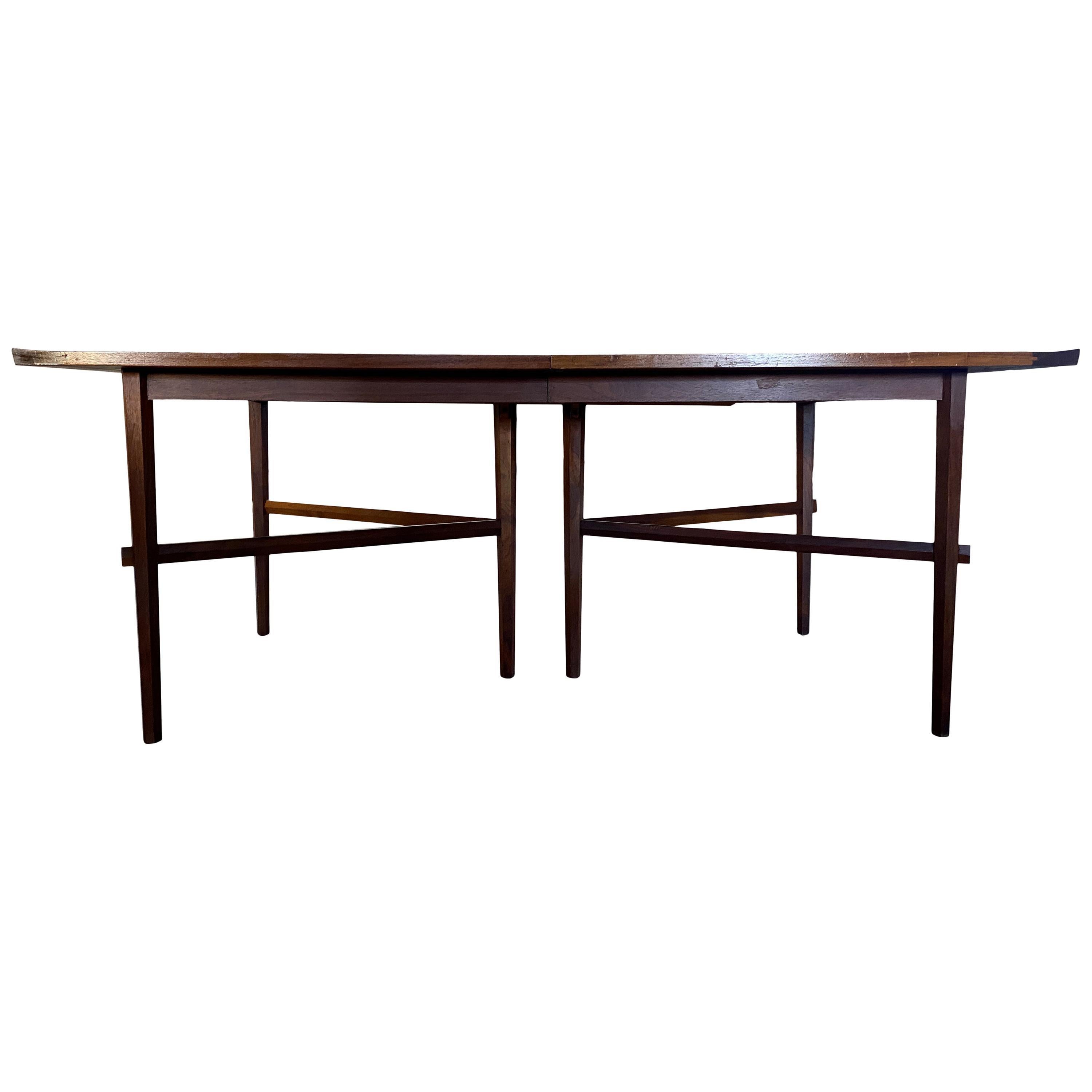Rare Widdicomb Mueller Titan dining table, attributed to George Nakashima dining table with an overall walnut finish, raised six tapered, hexagonal legs and hexagonal stretchers. Short end of the table has an edge that curves upward. Marked on