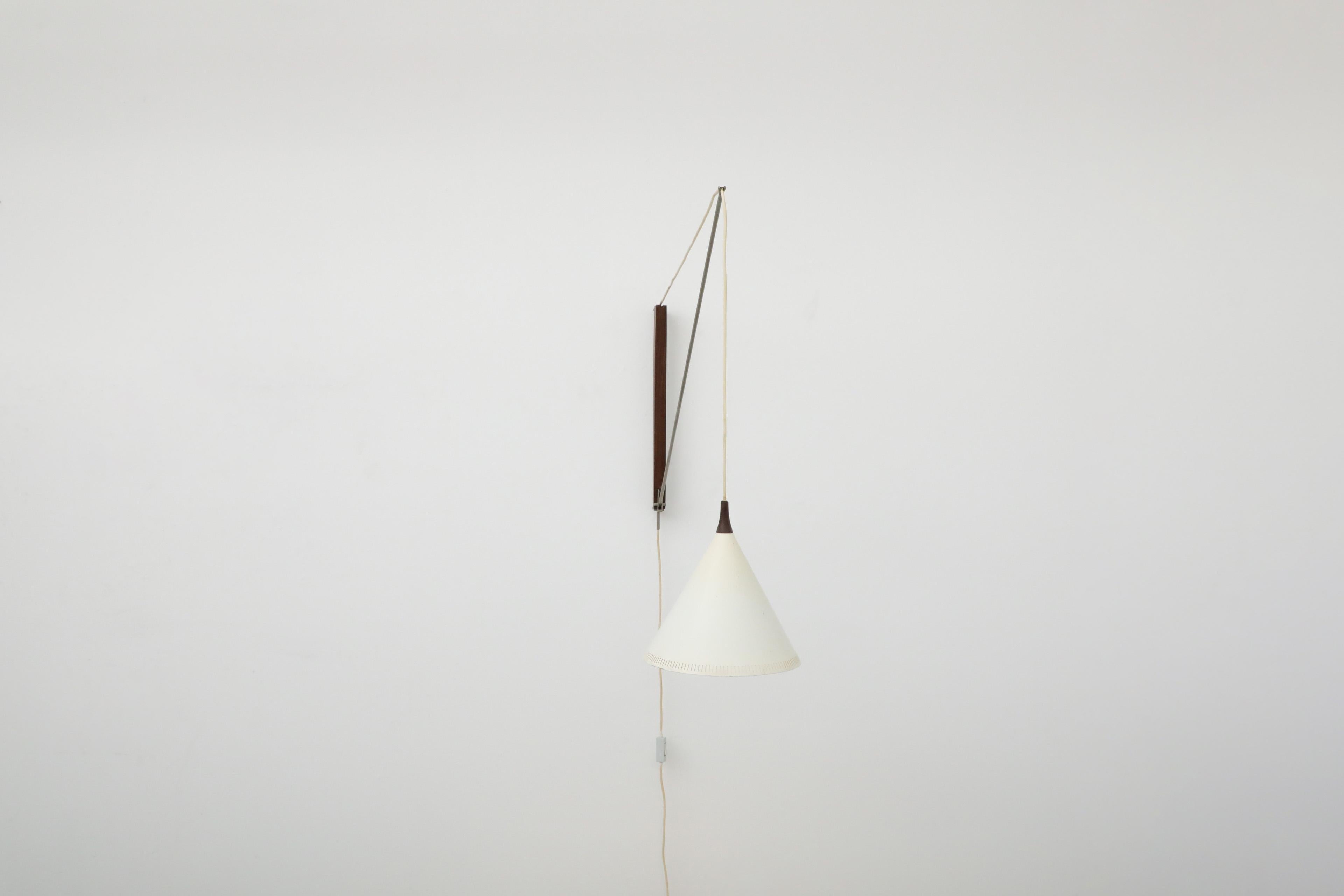 Bellissima applique Willem Hagoort con paralume a cono in metallo smaltato bianco su stelo in acciaio e supporto a parete in teak. Questa lampada incredibilmente costruita è girevole e può essere alzata o abbassata regolando il suo Corde, fornendo