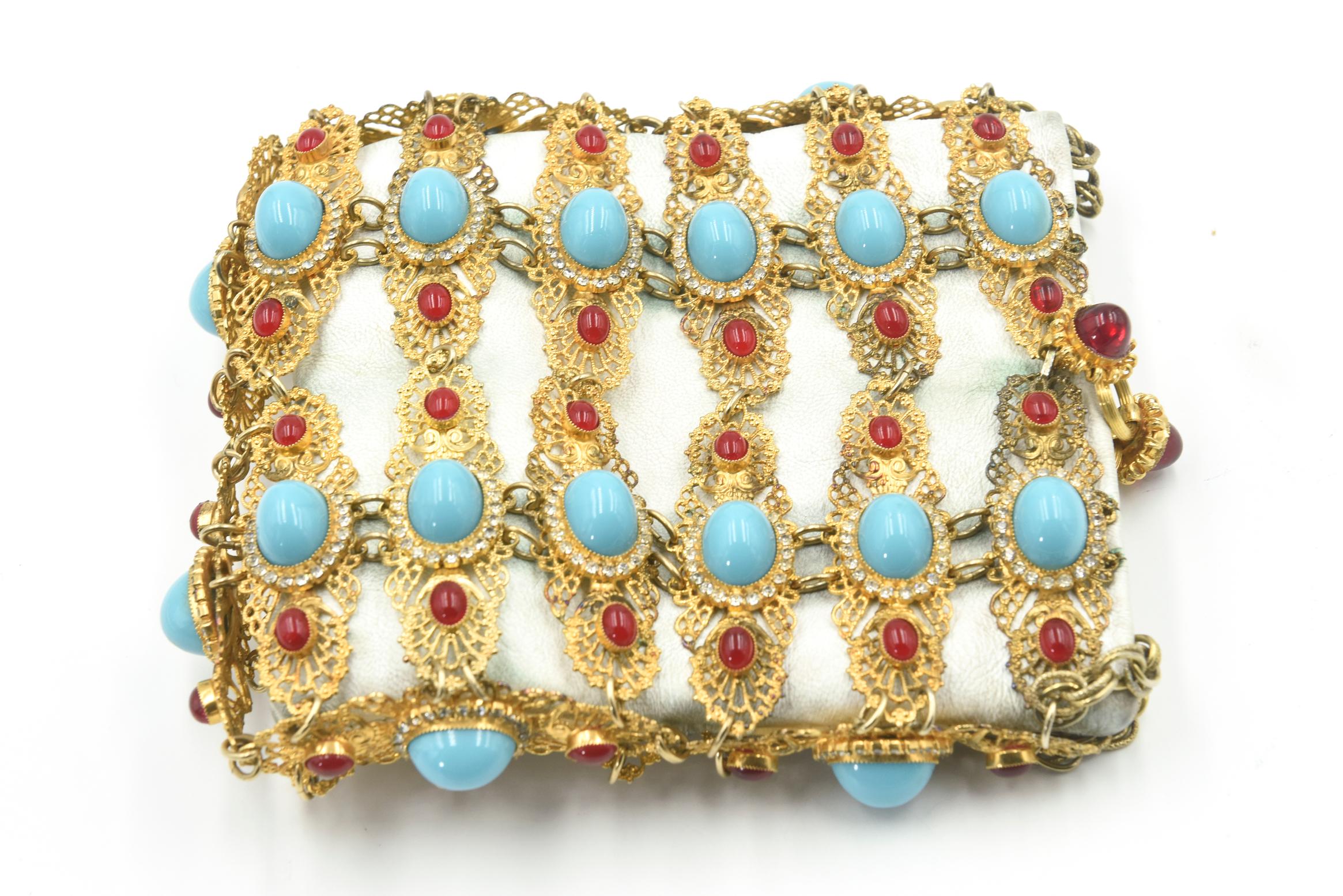 A unique (one of a kind) evening bag by William de Lillo.  The off white leather handbag is set within an ornate gilt metal and stone exterior bag.  It is comprised of a large oval faux turquoise (robin's egg blue) glass set in a rhinestone frame. 