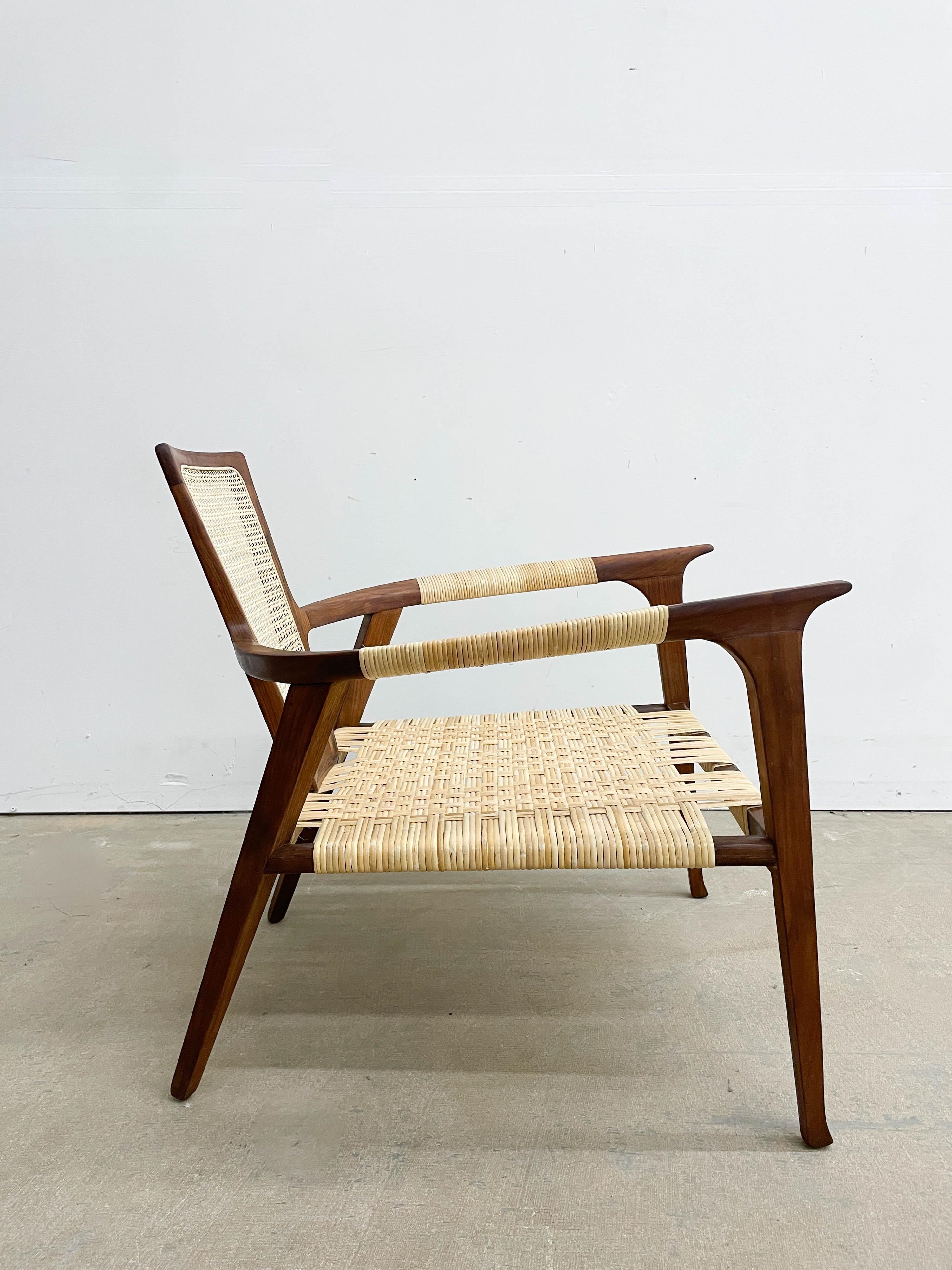 Rara silla diseñada por William Hinn para Urban Furniture hacia 1955. Fabricada en nogal macizo, con brazos y respaldo de caña, esta silla tiene curvas pronunciadas y algunos detalles realmente fantásticos que llaman la atención.  Nos hemos tomado