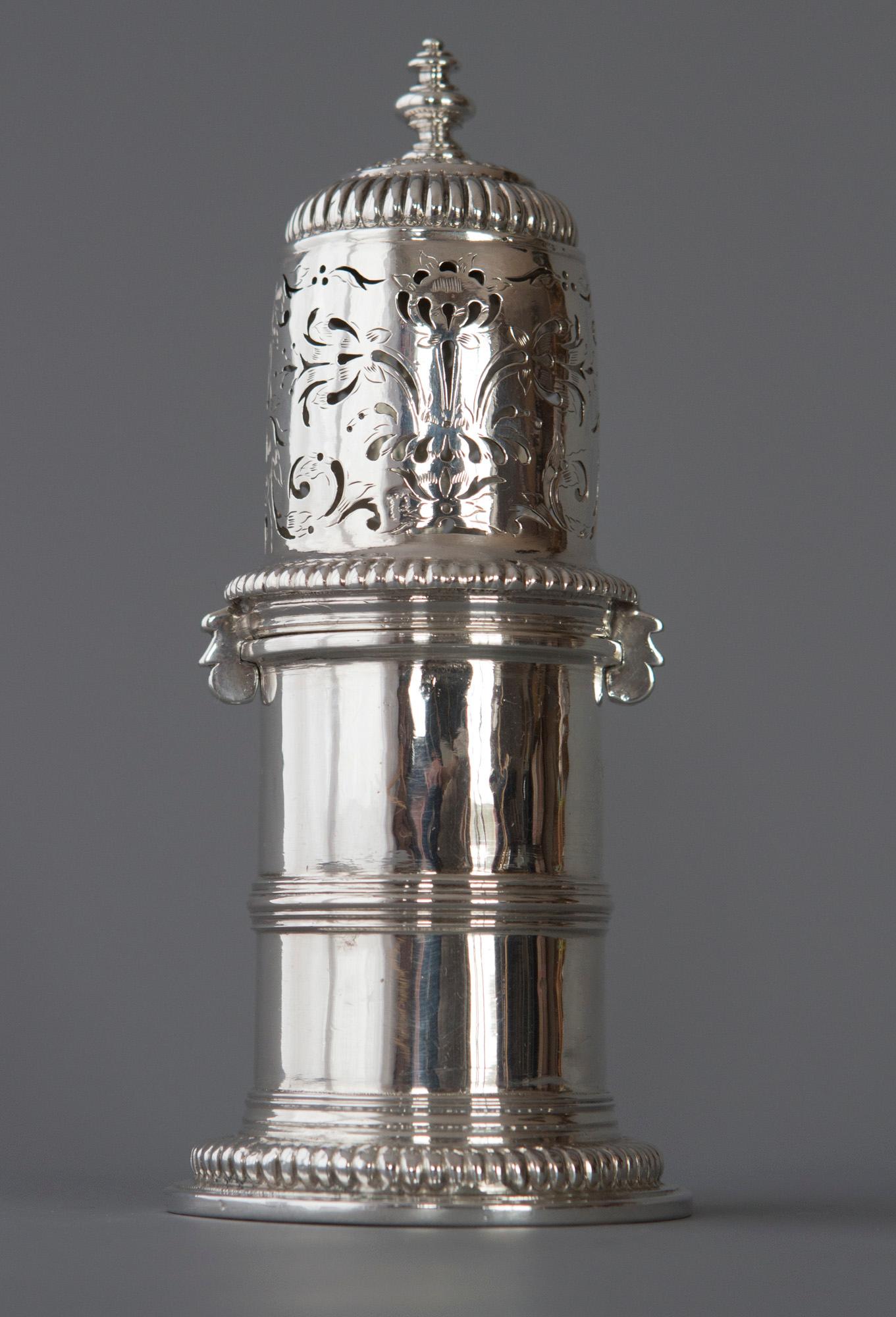 A very rare William III Britannia silver lighthouse caster, London 1698. Britannia Standard, with a turned finial to the domed, pierced cover engraved with scrolls and flowers with bayonet fixing mounts. The main body of the caster is plain with