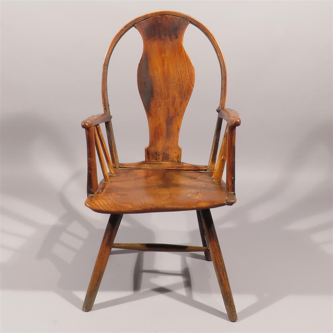 A rare windsor armchair with a grand solid shaped center back and stick arms on a looped frame, a gently
saddled elm shaped seat and splay legs joined by a ladder stretcher. Excellent color and form.