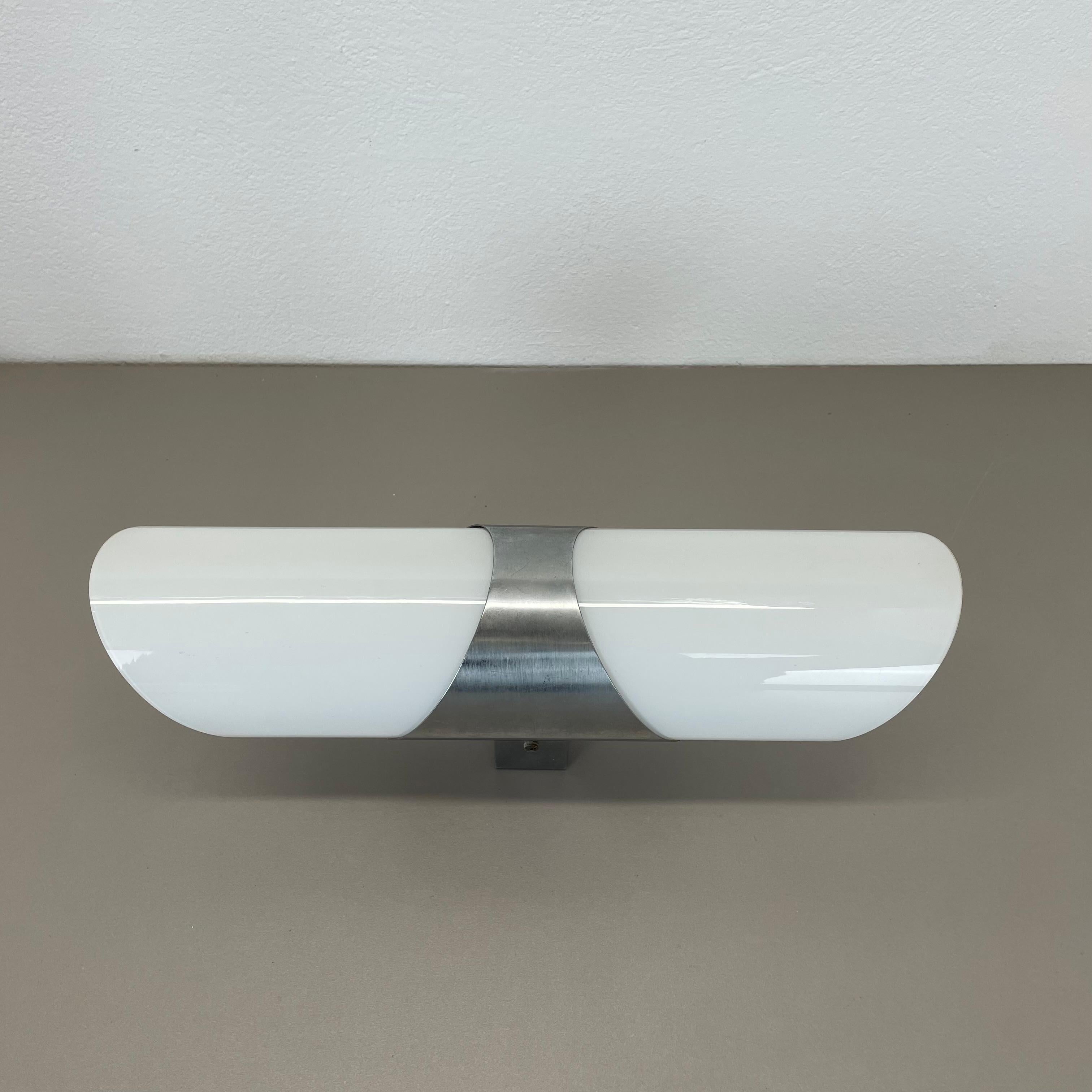 Article:

wall light with satin white glass shade


Origin: ITALY



Age:

1970s



This modernist light was produced in ITALY in the 1970s. It is made from solid silver tone metal  with 2 light sources covered by a satin white glass shade element.