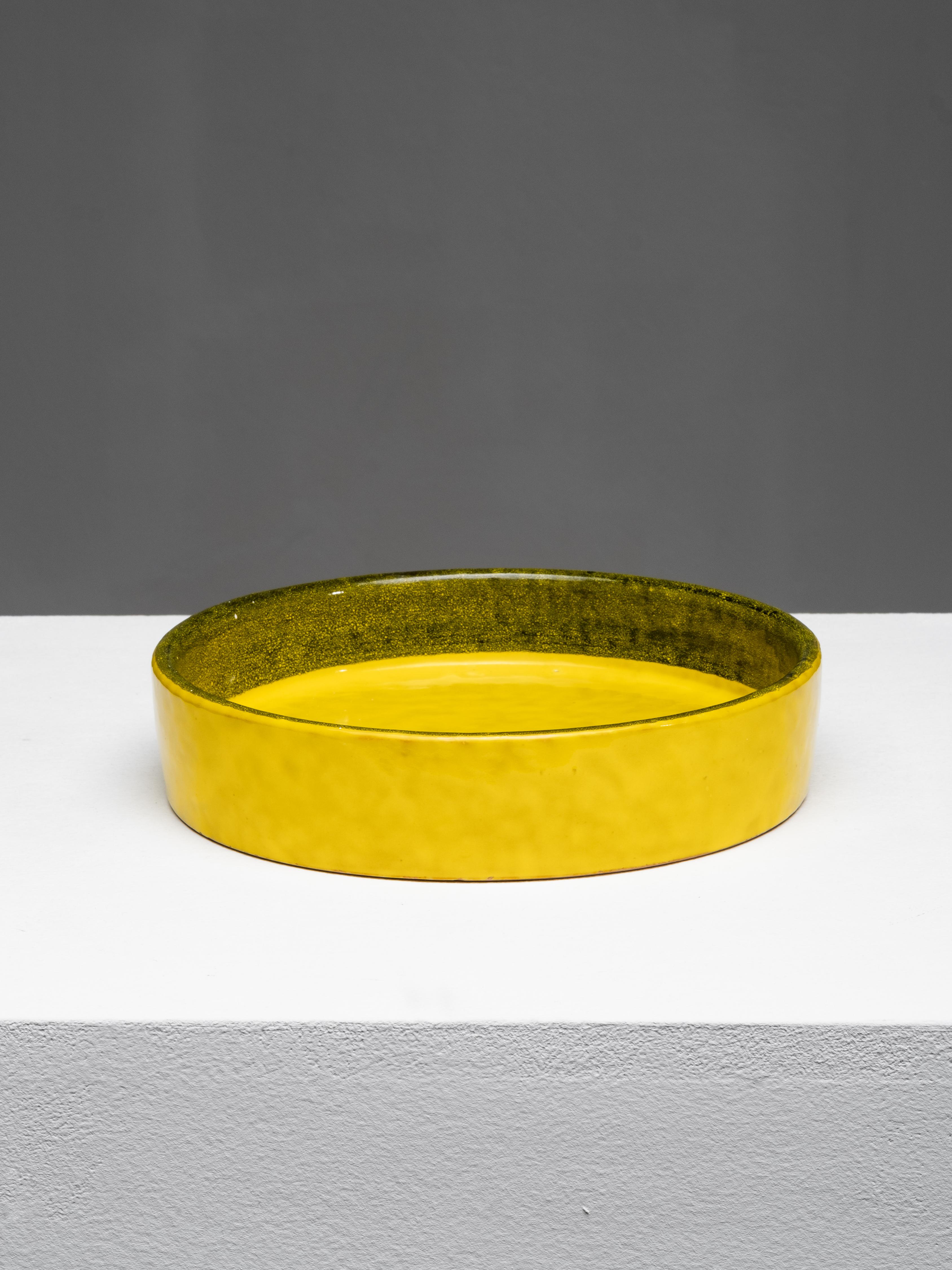 Seltene runde Keramikschale, entworfen von Aldo Londi für Bitossi, Montelupo Fiorentino, Italien, 1960er Jahre. Das Stück weist eine leuchtend gelbe Glasur mit einem olivgrünen Innenrand auf, die auf einen dunklen Engobegrund aufgetragen wurde - ein