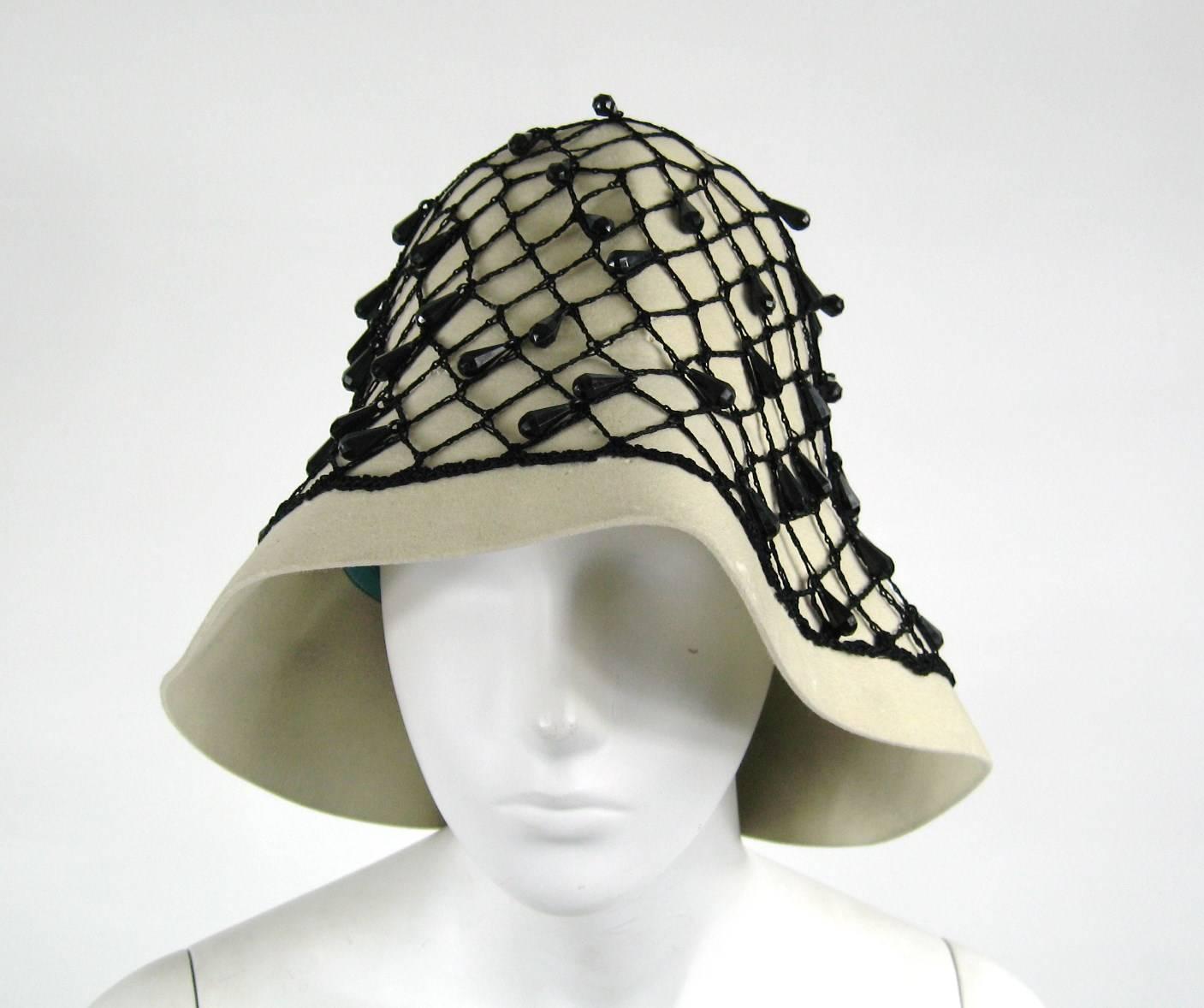 Stunning YSL Vintage Beaded Hat. Black Netted beading with a Ribbon Bow at the back. Cream wool fabric. Saks Fifth Ave label as well as YSL label Finished with a narrow turquoise grosgrain ribbon. Aside from being decorative, it serves to adjust the