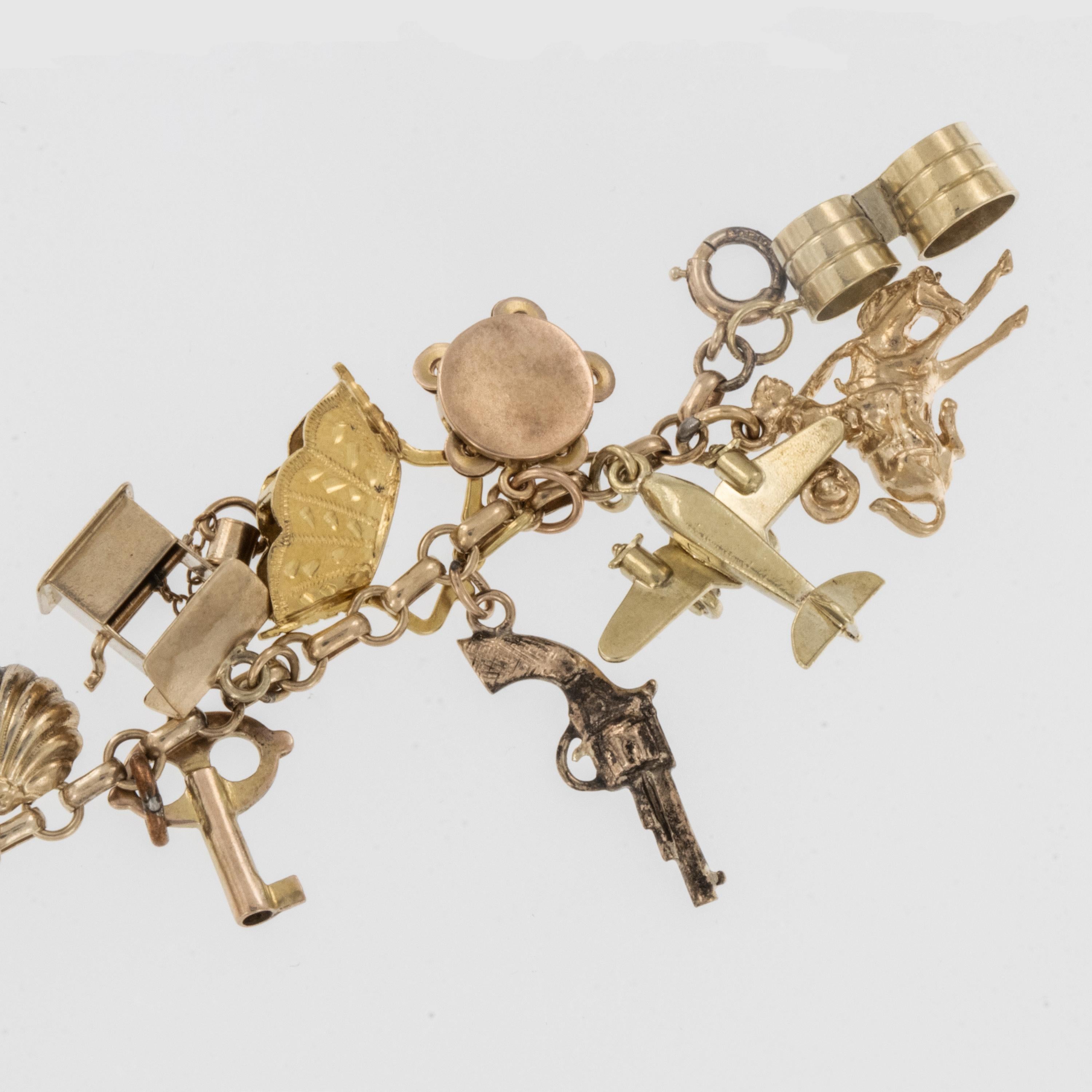 Ils ne sont plus fabriqués comme ça ! Ce bracelet à breloques des années 1930, monté sur une chaîne Belcher plate d'origine, comporte 26 breloques originales. La plupart sont en 14 carats, 1 en 18 carats, 1 en argent et quelques uns en 10 carats. Il