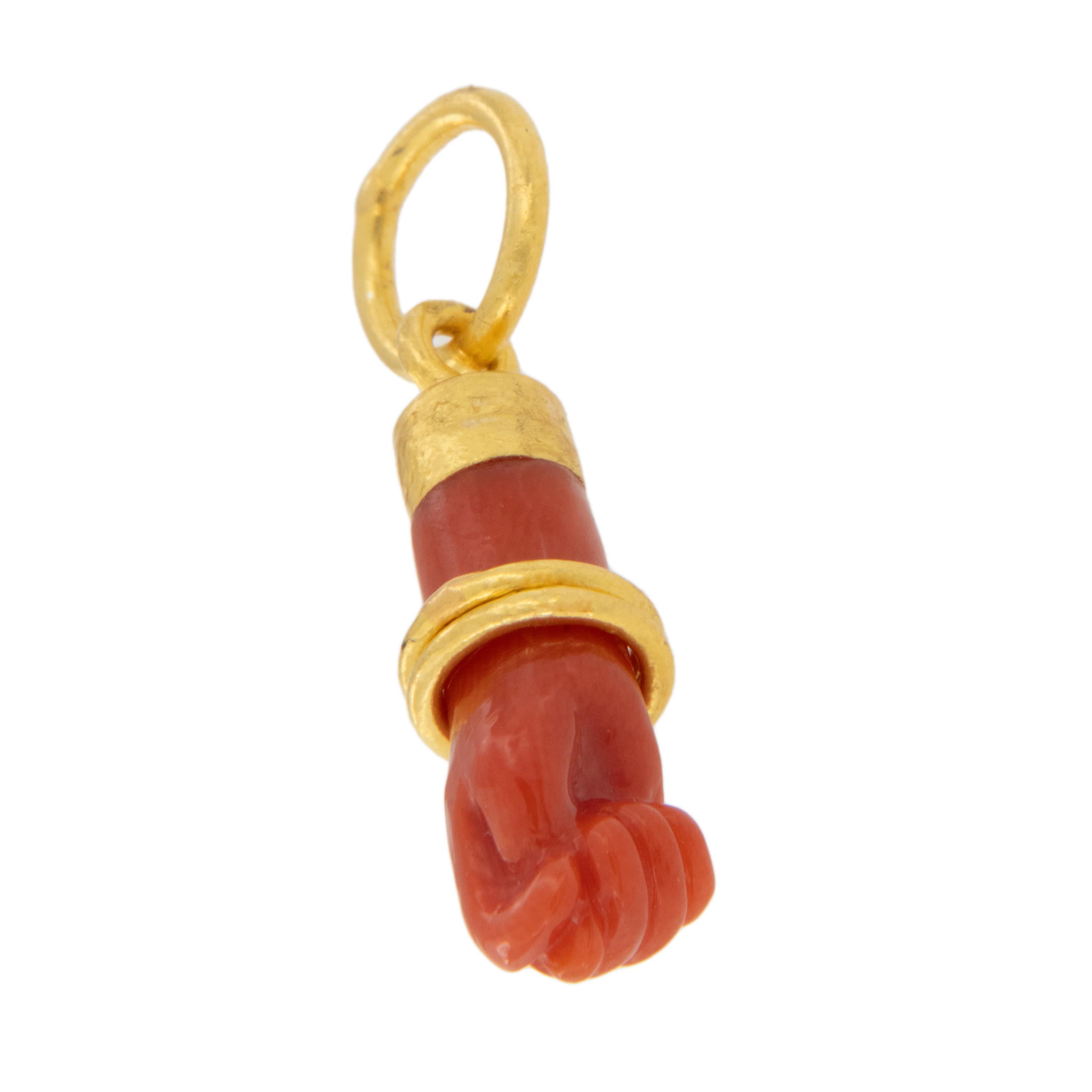 Hand carved from beautiful Mediterranean coral, this figa pendant is accented with a pure 24 karat yellow gold 