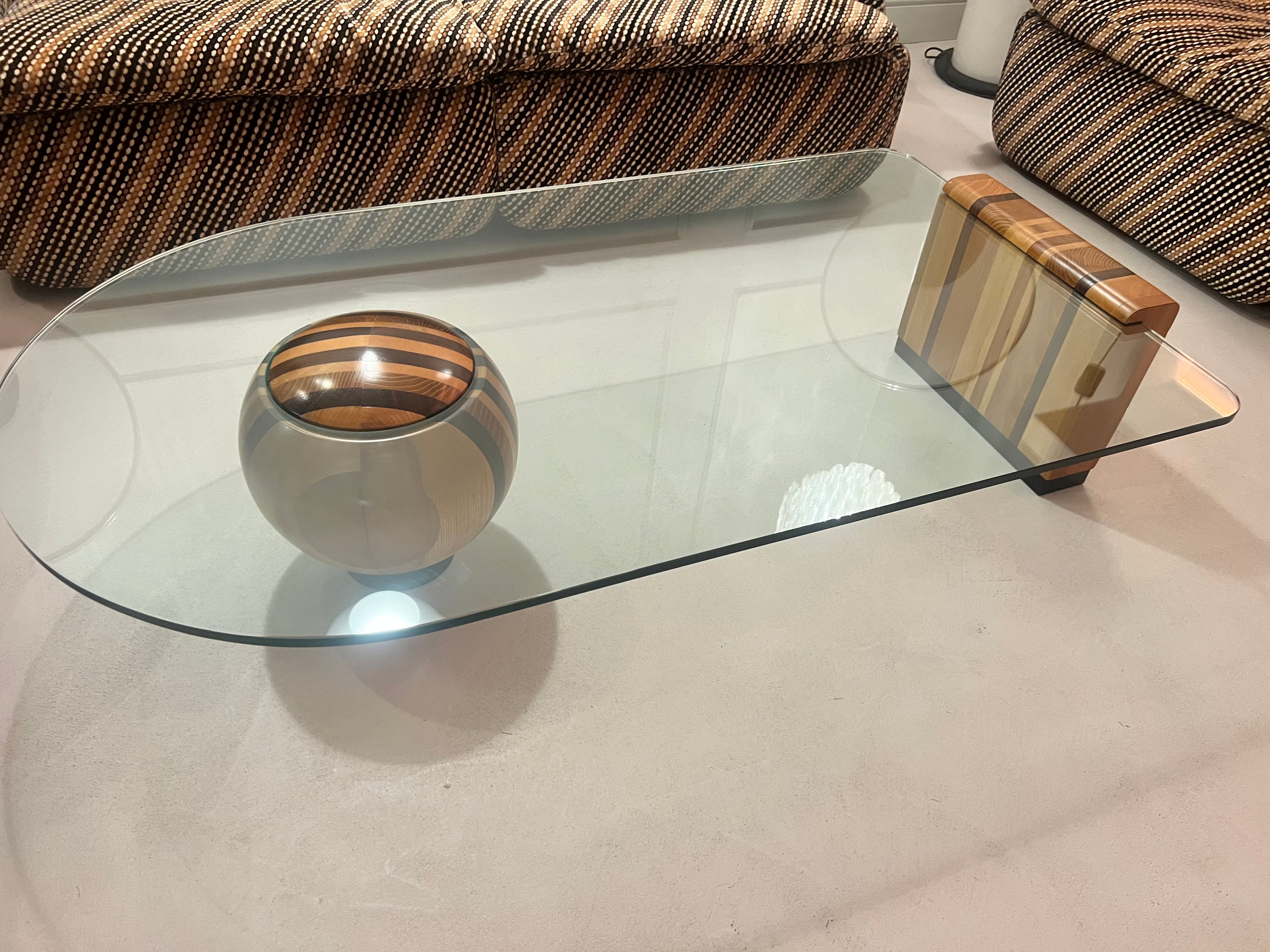 Rarissimo tavolino di Massimo e Lella Vignelli prodotto da Casigliani negli anni Settanta in Italia. Il tavolino è composto da tre pezzi: una ciotola, un elemento di base costituito da diverse fette di legno e il piano in vetro. Il piano in vetro è
