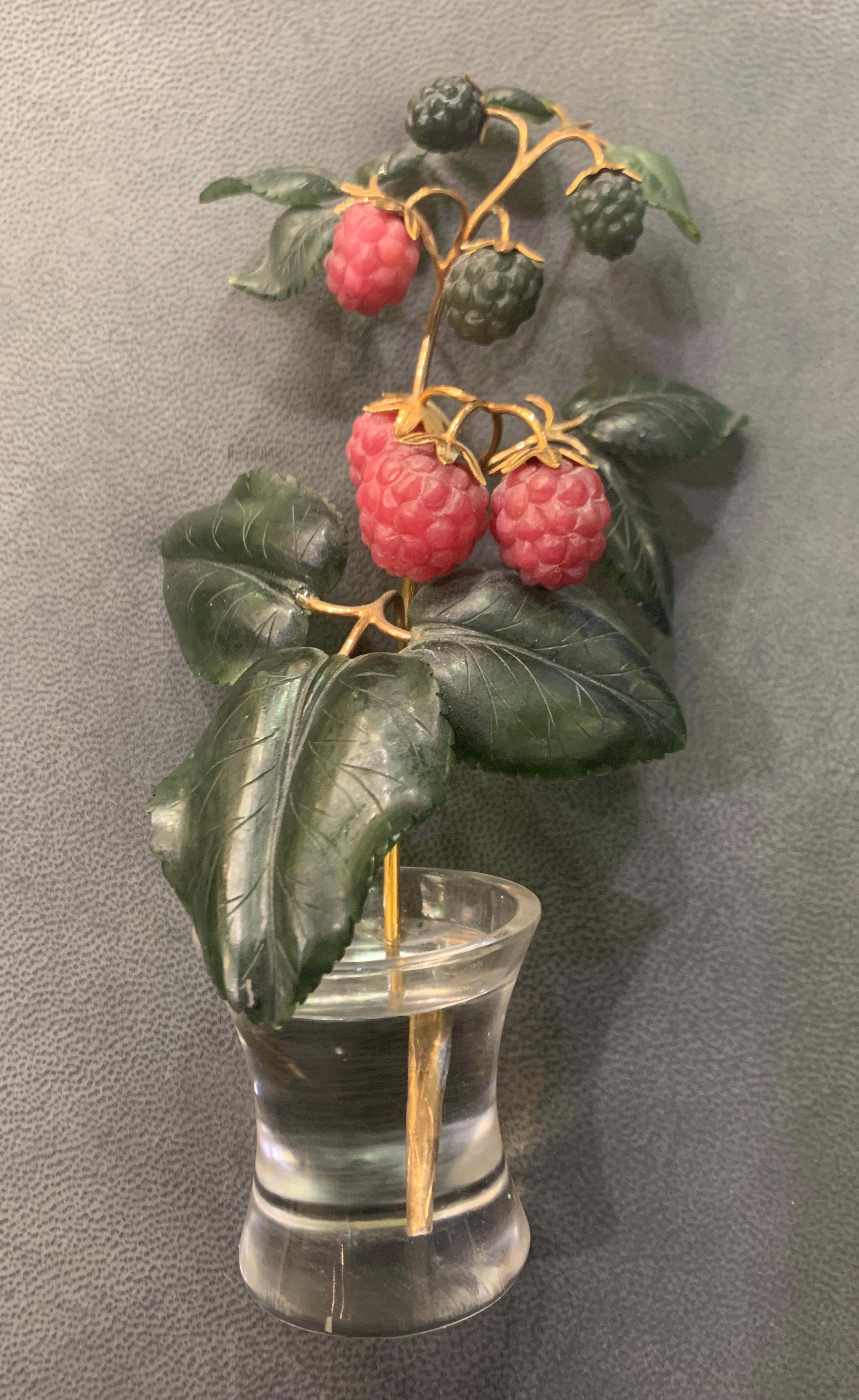 Raspberry Flower Pot

A miniature flower pot crafted from rock crystal, showcasing carved red rhodochrosite raspberries
and green nephrite leaves. Set with a gold stem in a rock crystal pot designed to create a water illusion.

Measurements: 6