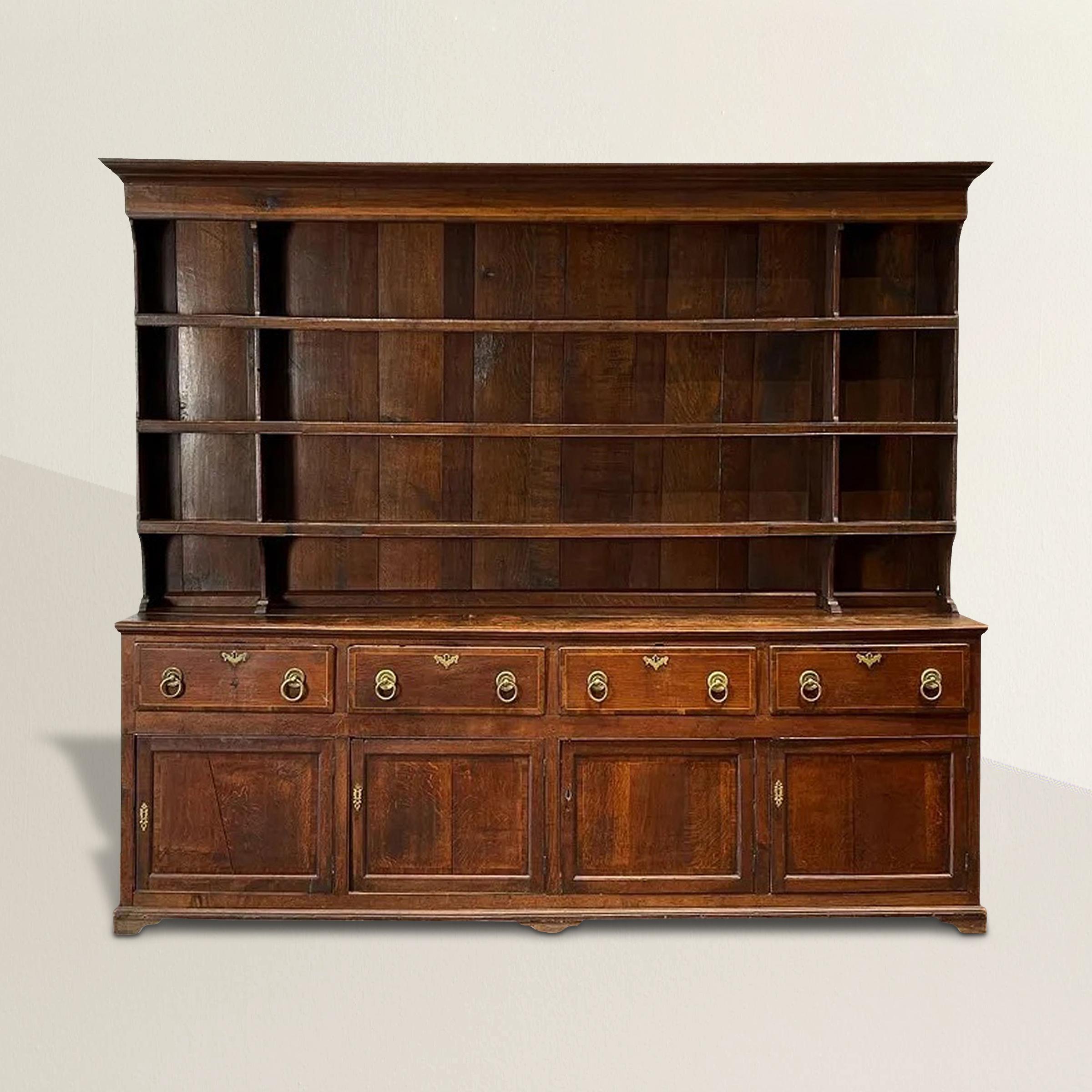 A stunning rather large late-18th century Welsh George III oak dresser constructed in three parts with a top plate rack over a bank of four large drawers with inlaid fruitwood and large brass pulls, and all over a lower section with four doors. This